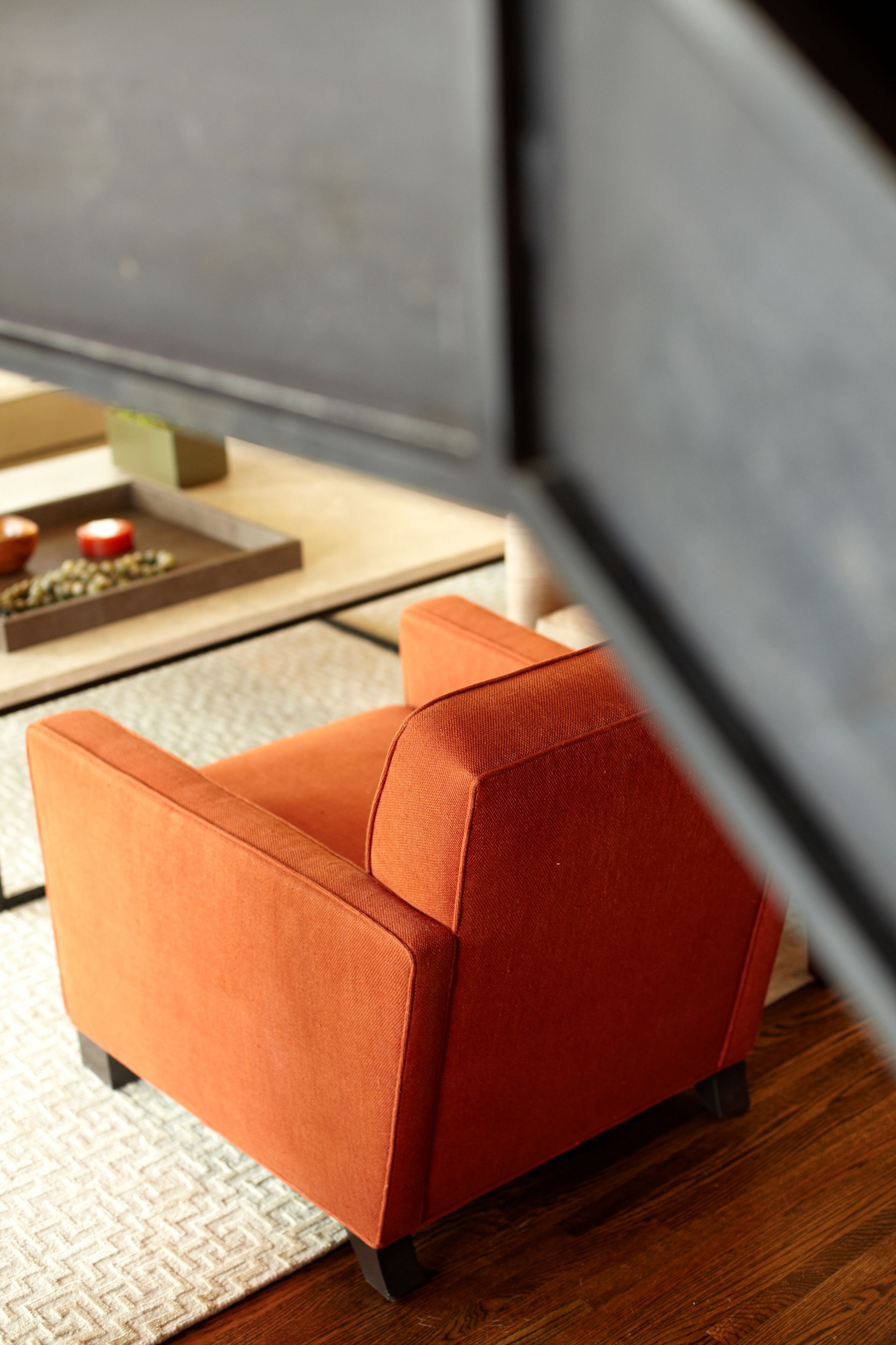 An orange chair is sitting in a living room next to a coffee table