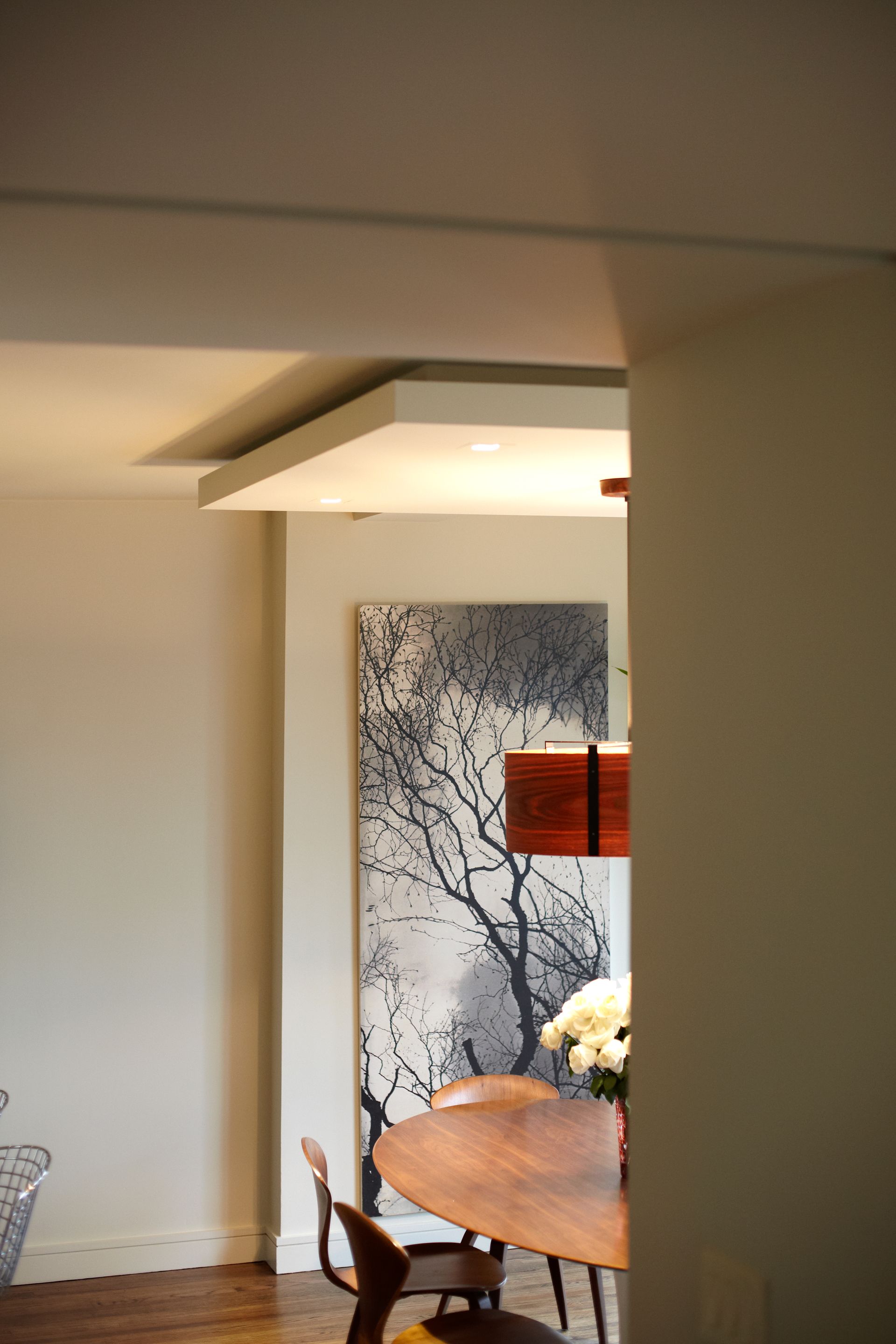 A dining room with a table and chairs and a painting on the wall.