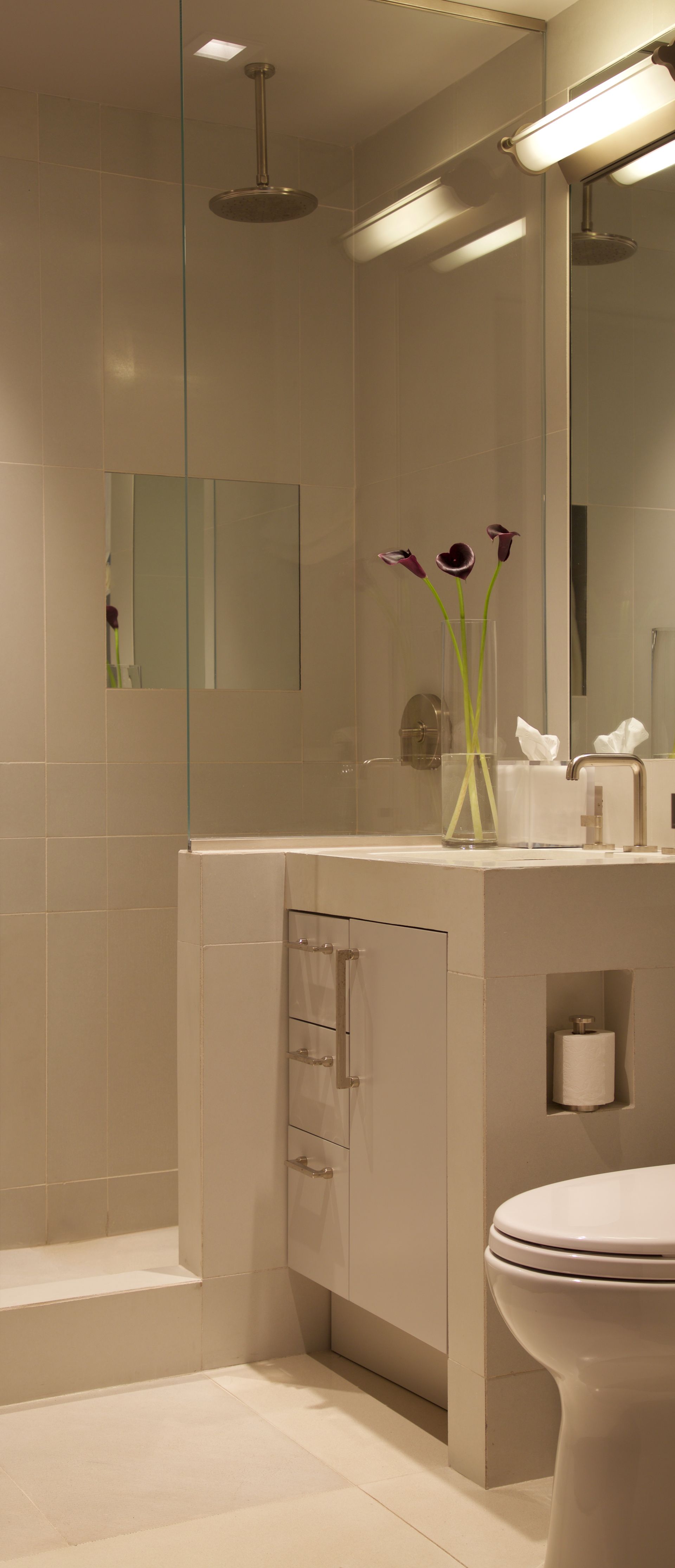 A bathroom with a toilet , sink , shower and mirror.