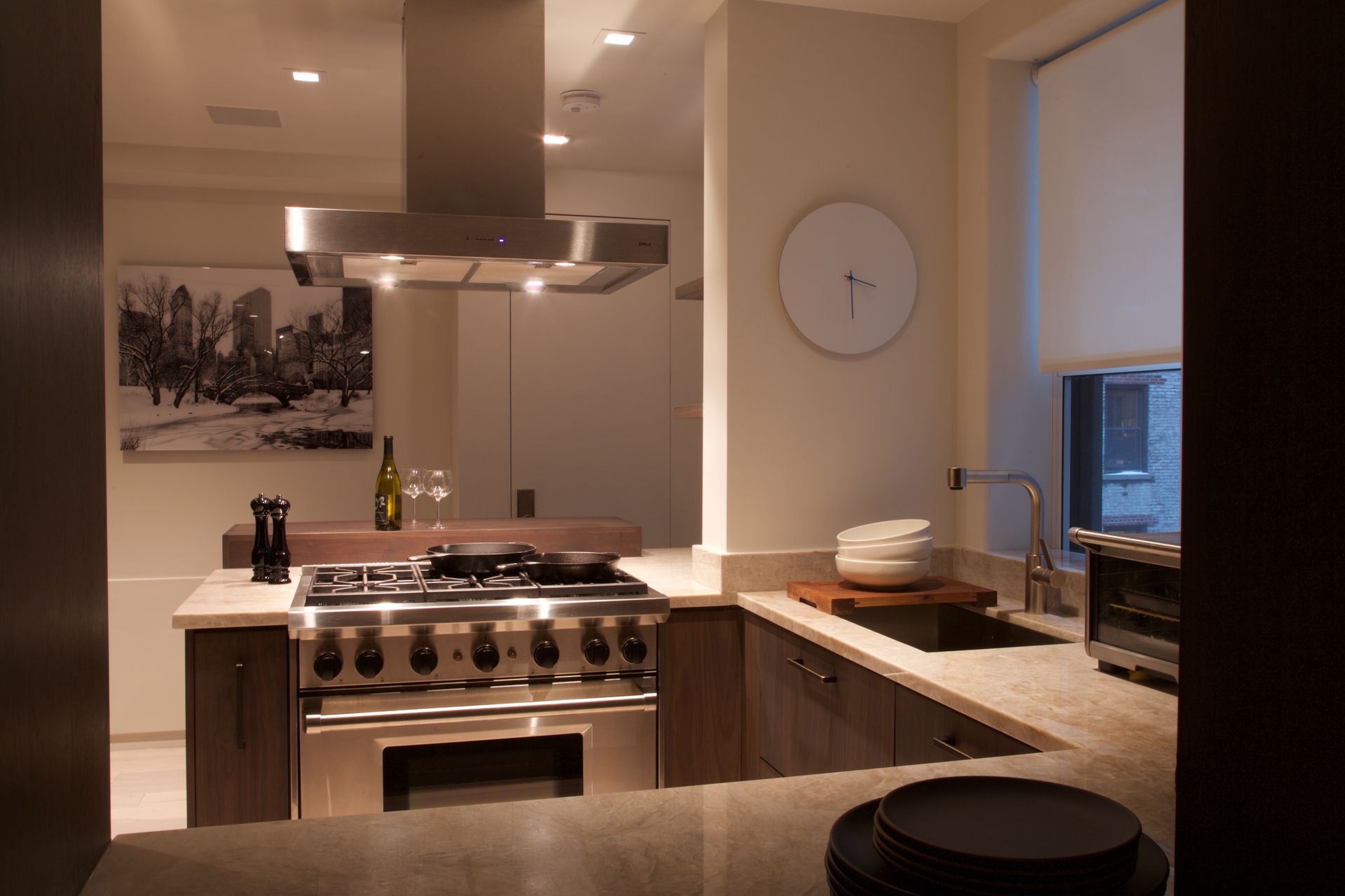 A kitchen with stainless steel appliances and a clock on the wall