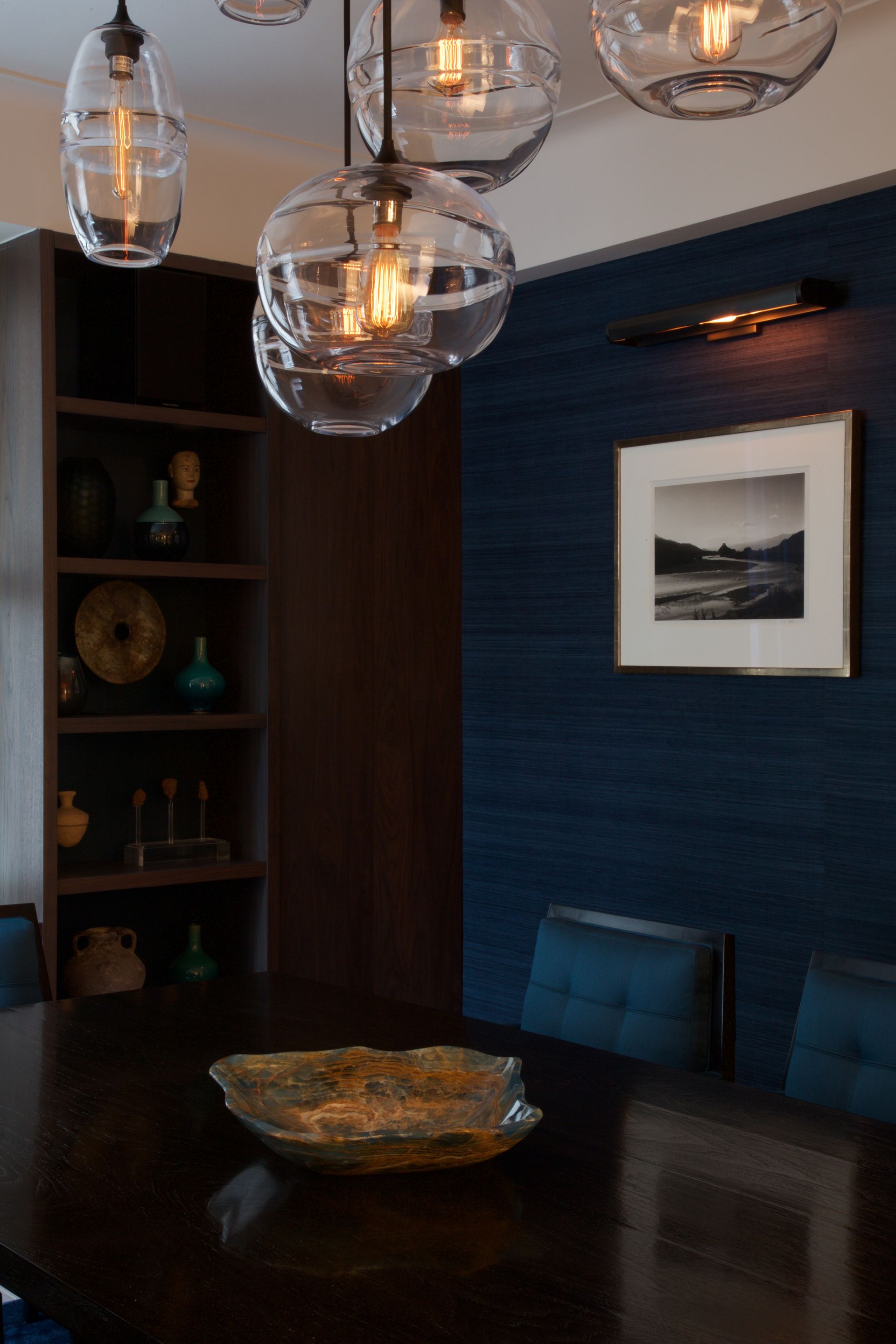 A dining room with a table and chairs and a picture on the wall