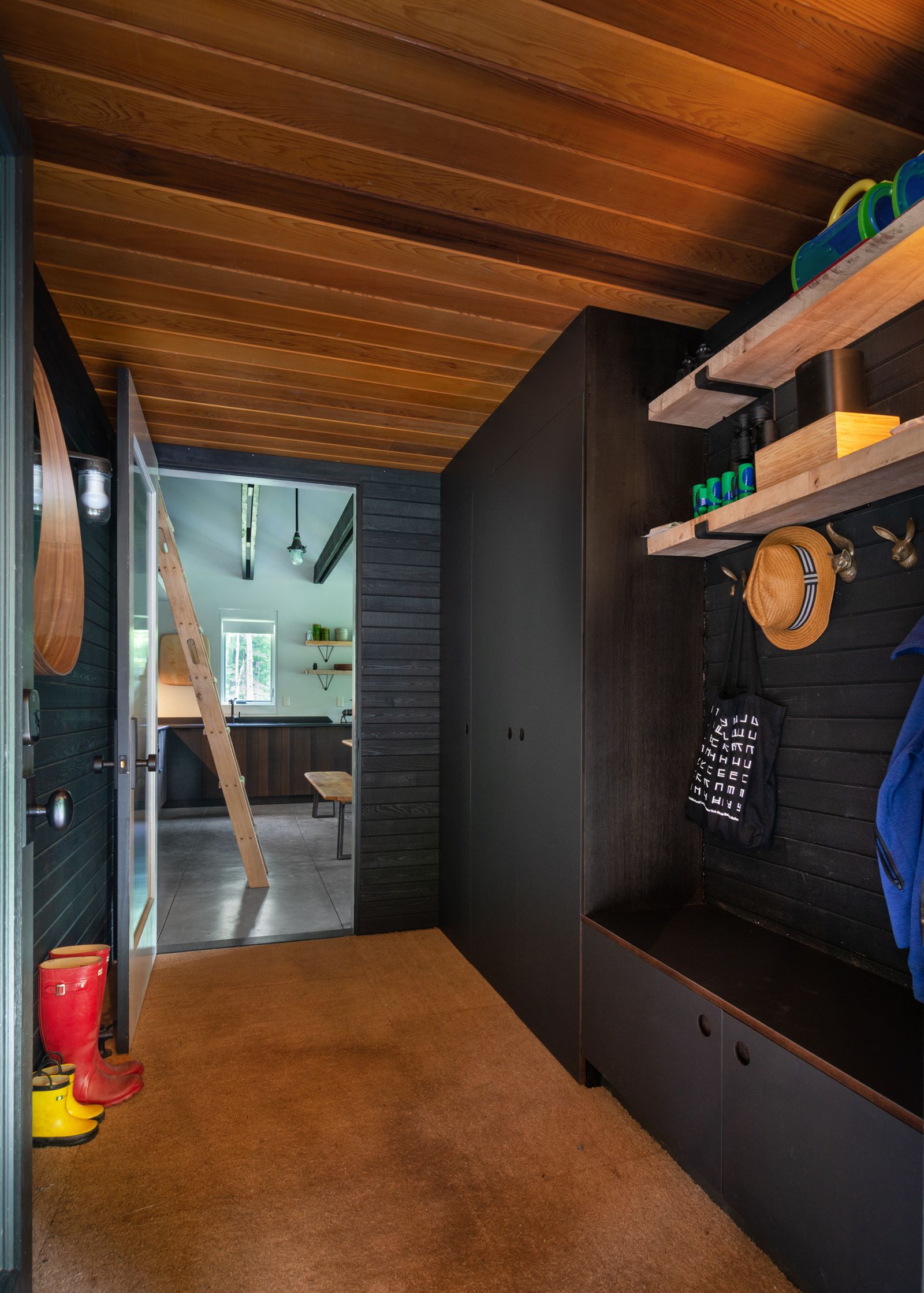 A hallway with a wooden ceiling , shelves , and a bench.