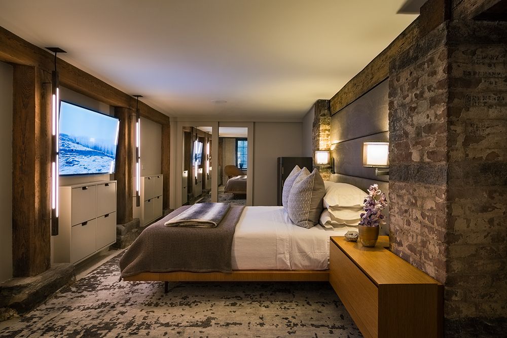 A bedroom with a large bed and a television on the wall.