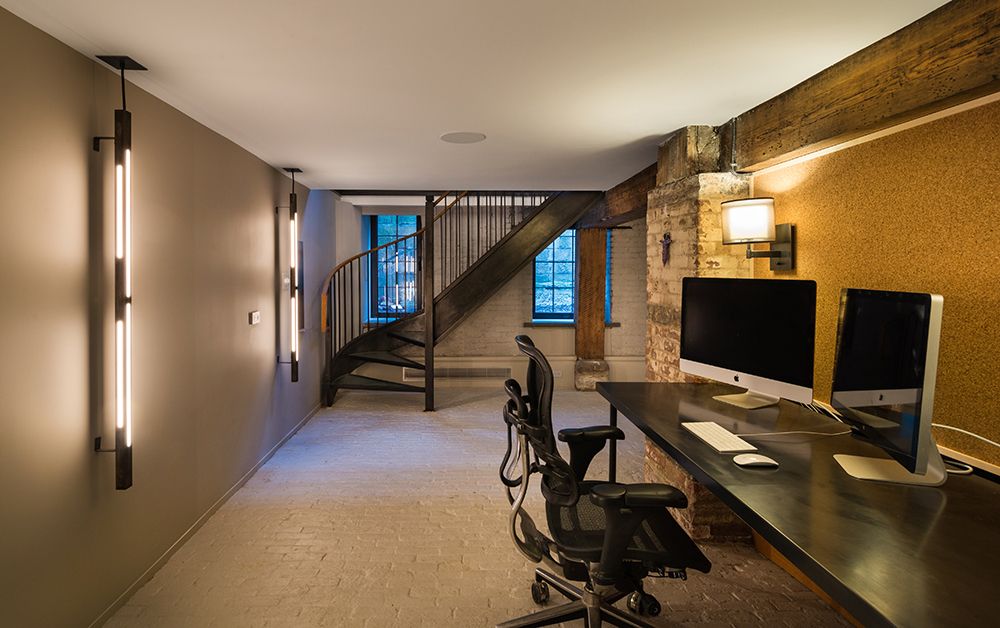 A room with a desk , chair , computer and stairs.