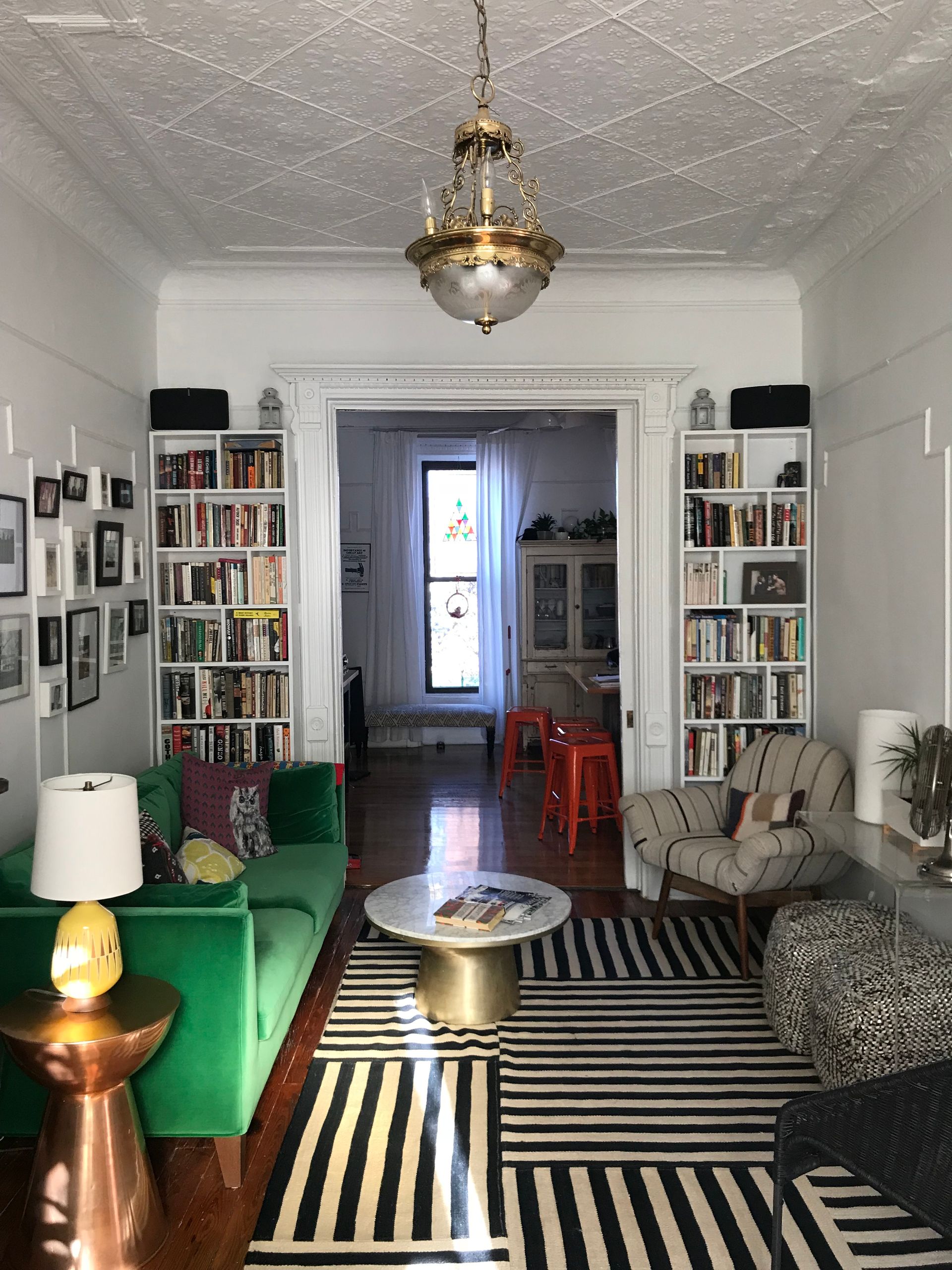 A living room with a green couch and a black and white rug