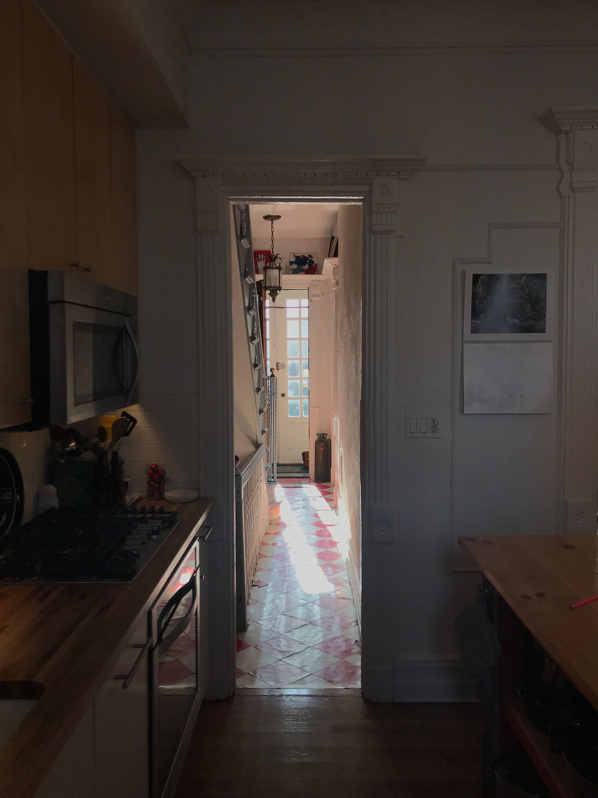 A kitchen with a microwave and a calendar on the wall