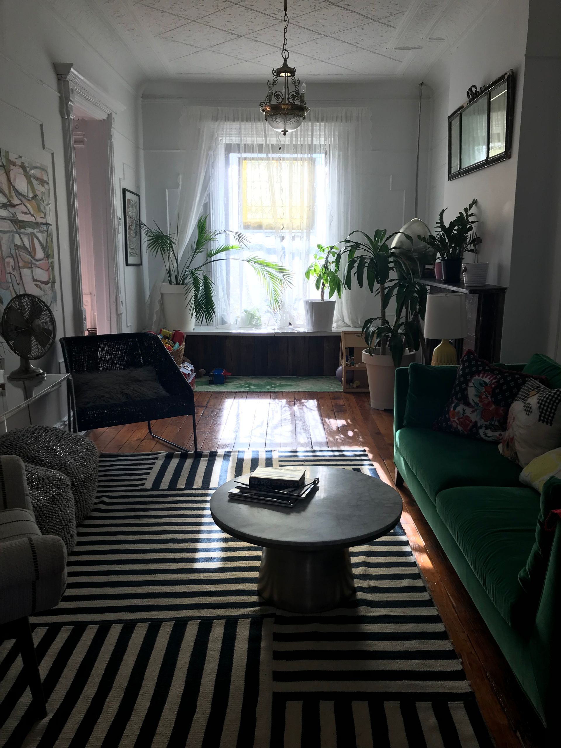 A living room with a green couch and a black and white rug
