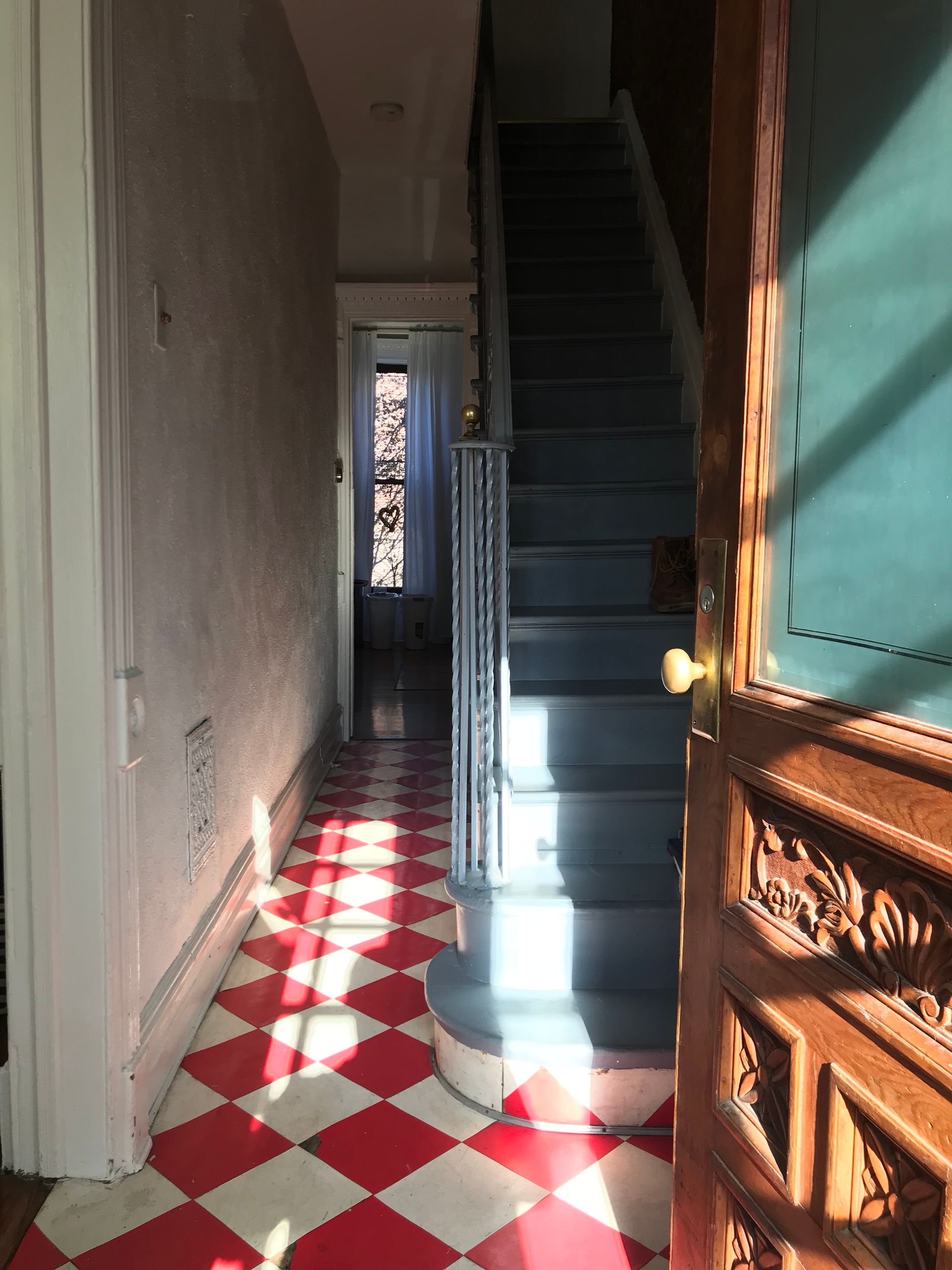 A hallway with red and white checkered floors and stairs