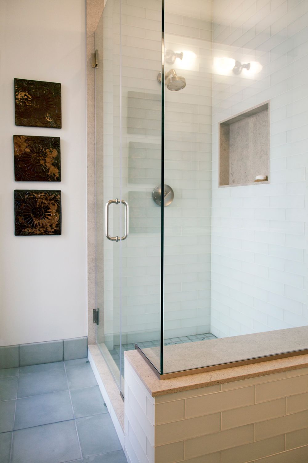 A bathroom with a walk in shower with a glass door.