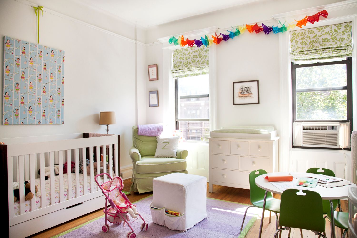 A child 's room with a crib , chair , table and chairs.