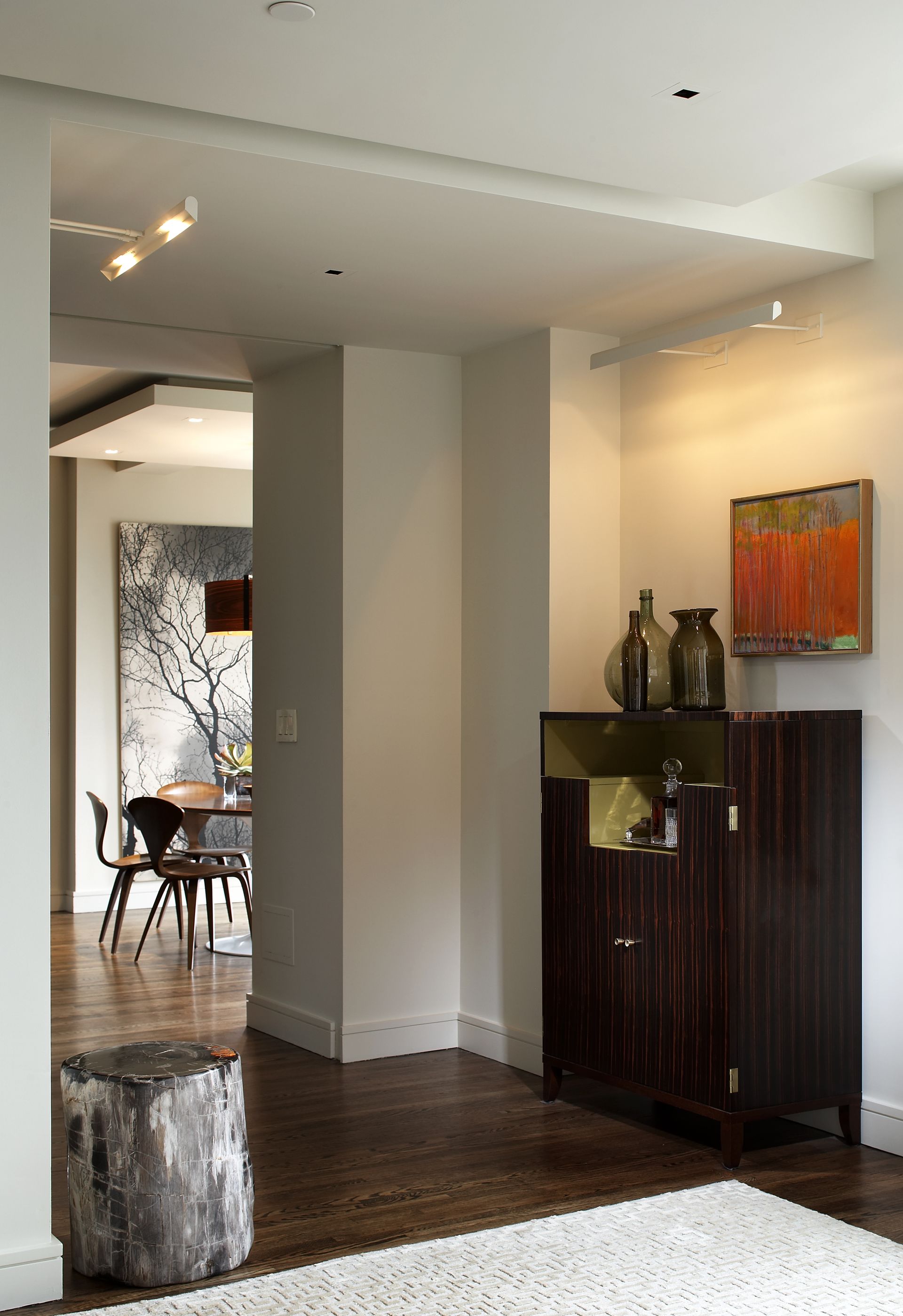 A living room with a stump on the floor and a painting on the wall