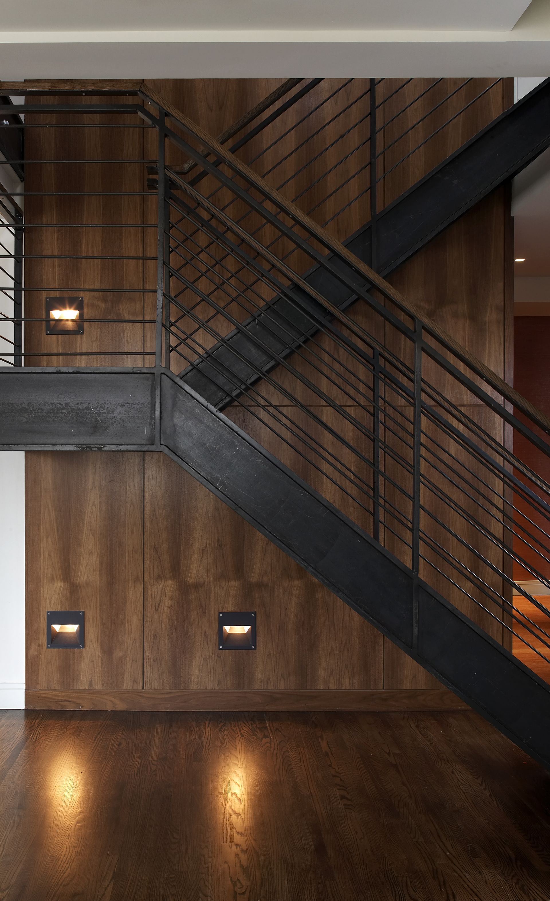 A staircase with a wooden wall and a metal railing.