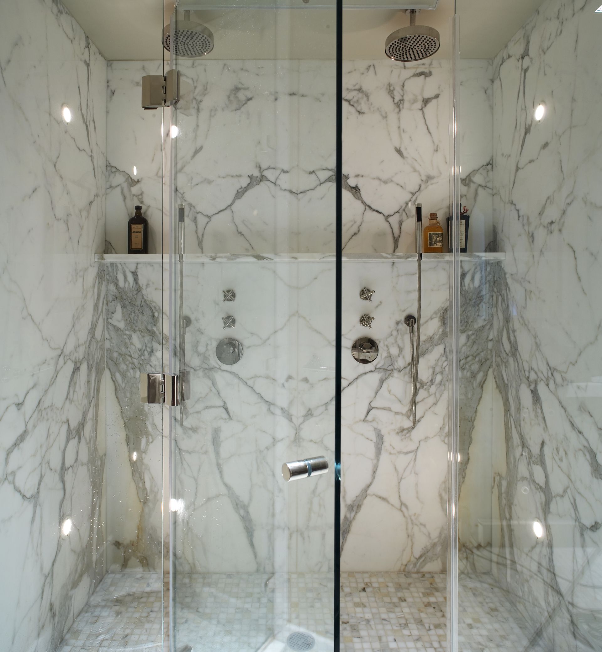 A shower stall with marble walls and a glass door