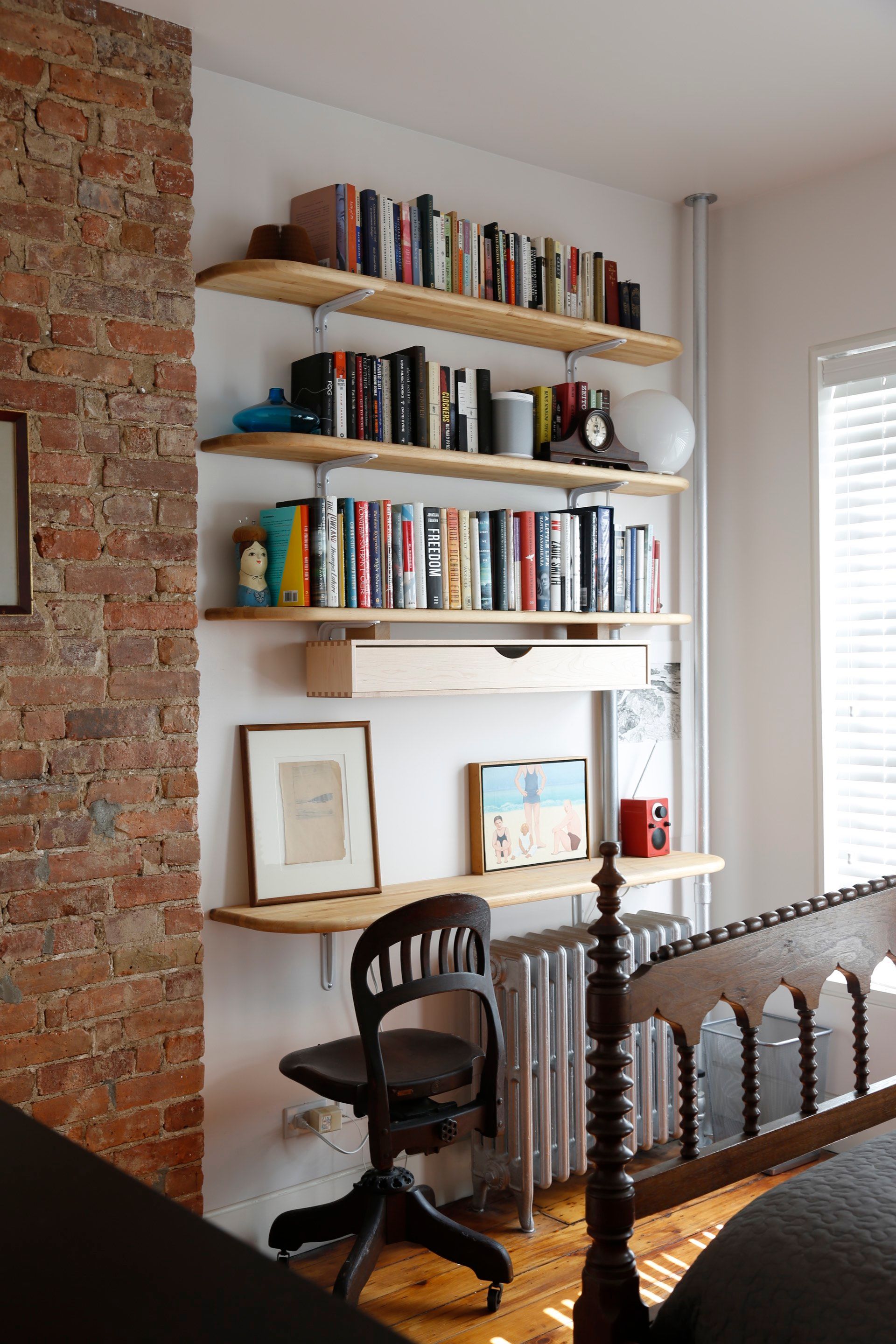 A bedroom with a brick wall and shelves filled with books