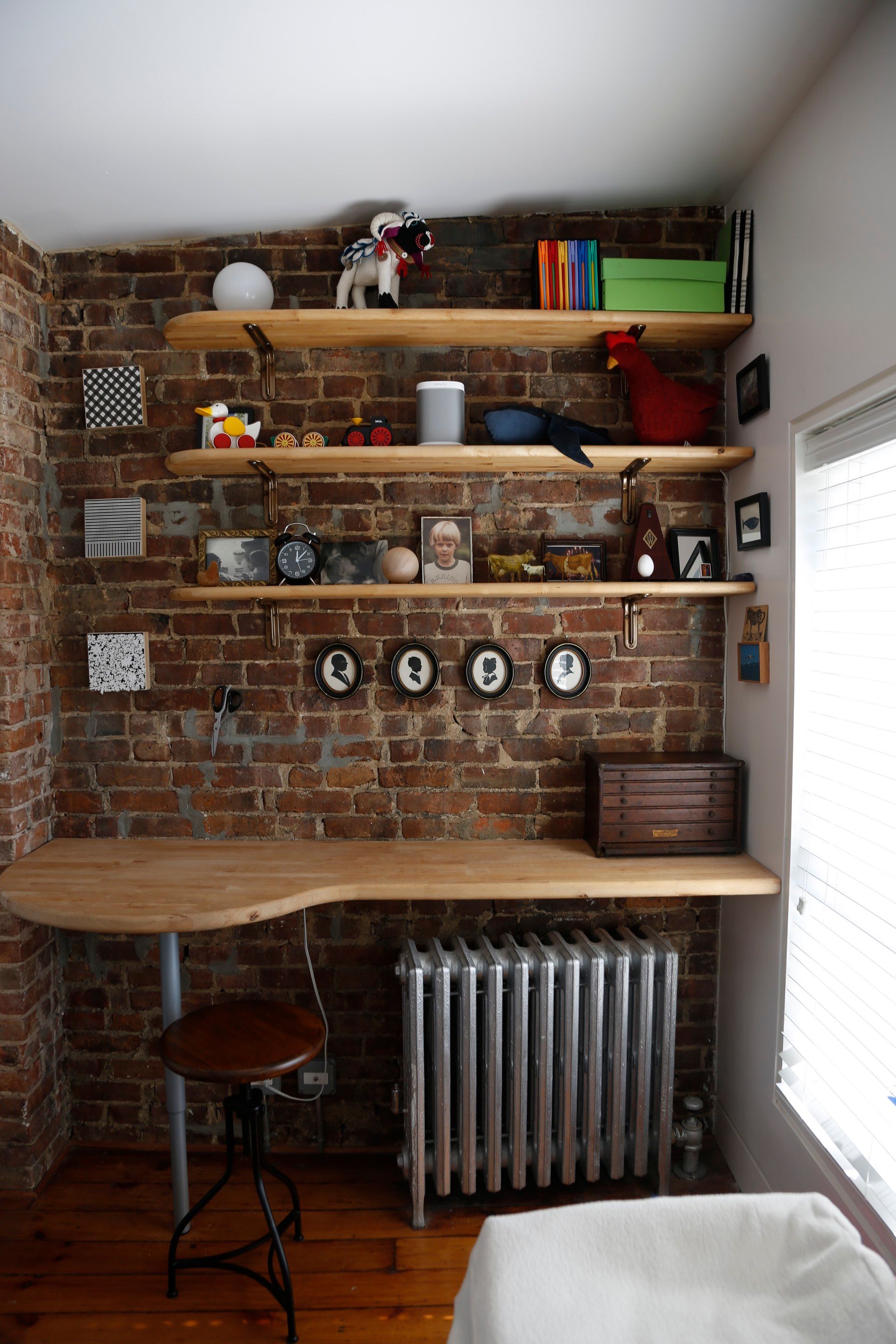 A room with a brick wall a desk and a radiator