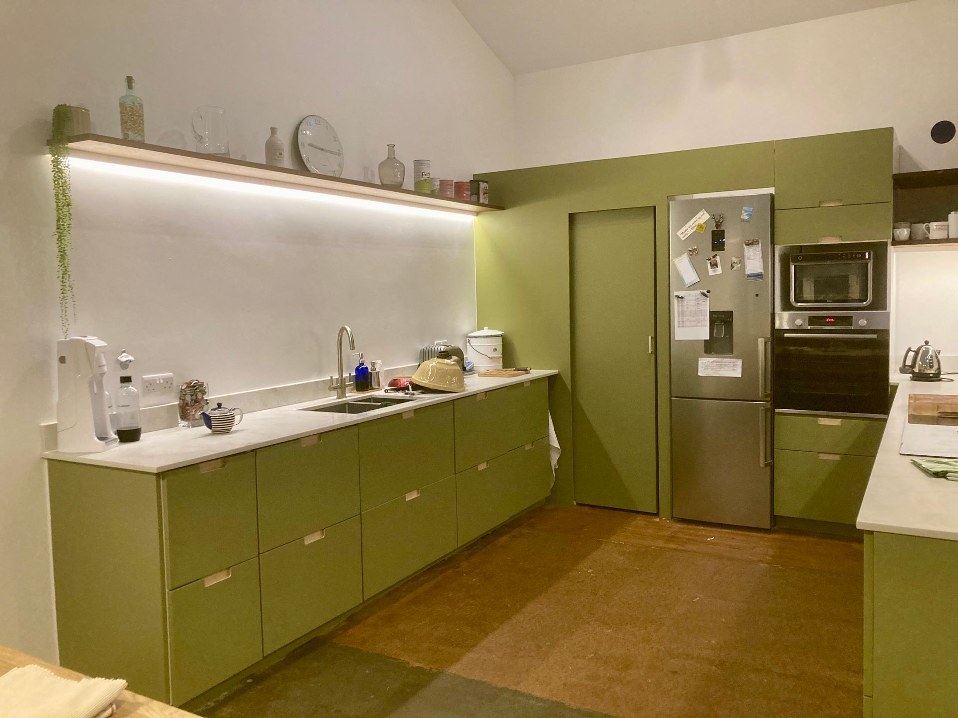 A kitchen with green cabinets and a stainless steel refrigerator