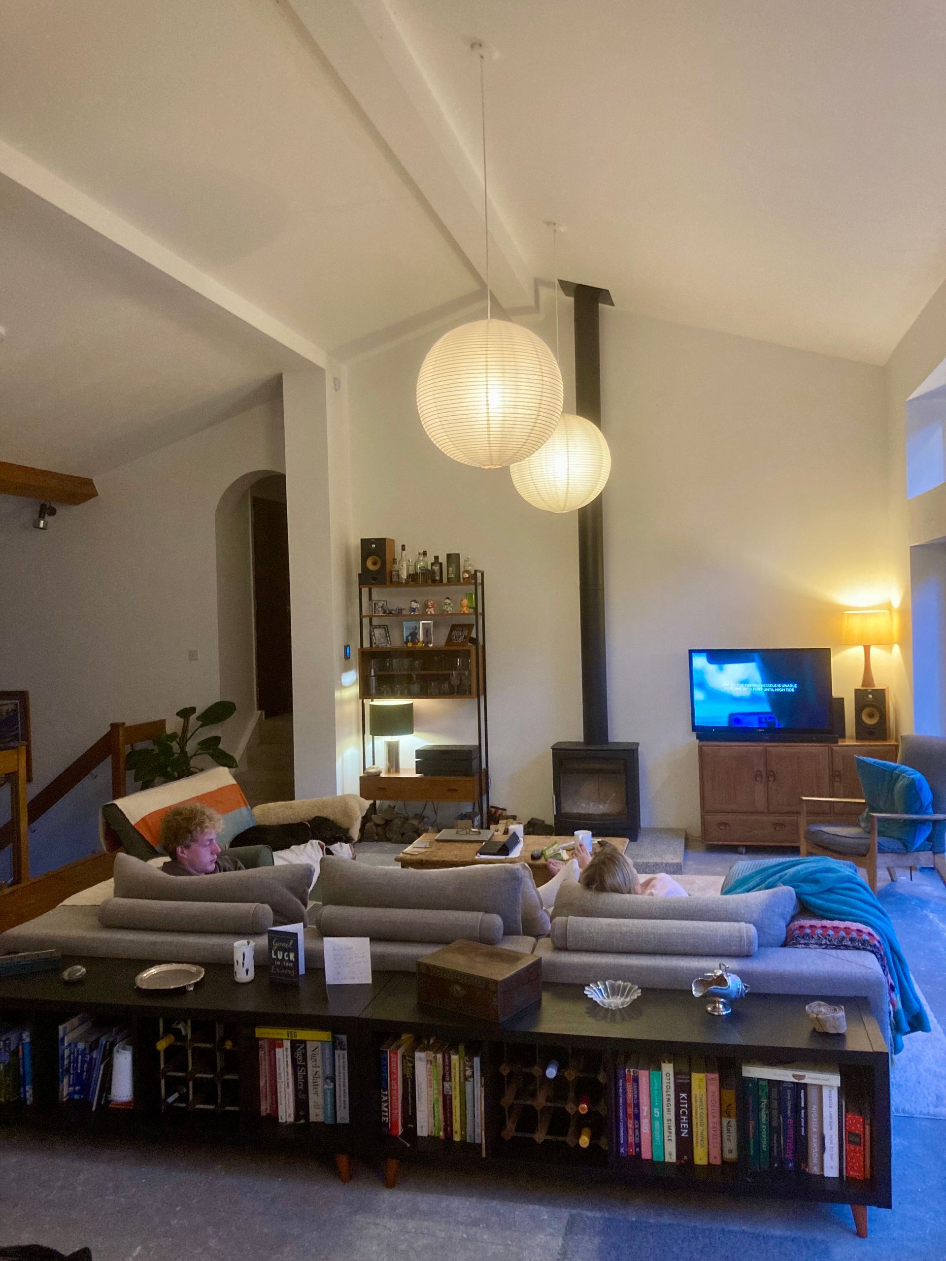 A living room with a couch , bookshelf , television and fireplace.
