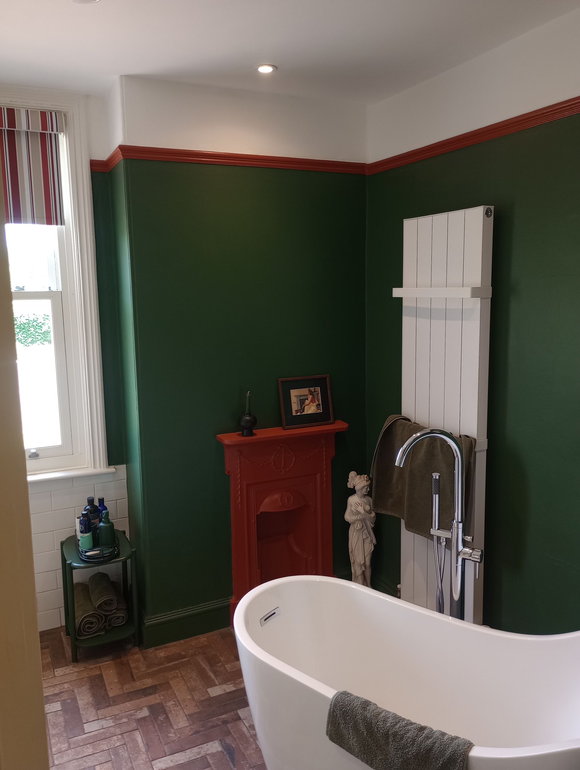A bathroom with green walls , a fireplace and a bathtub.