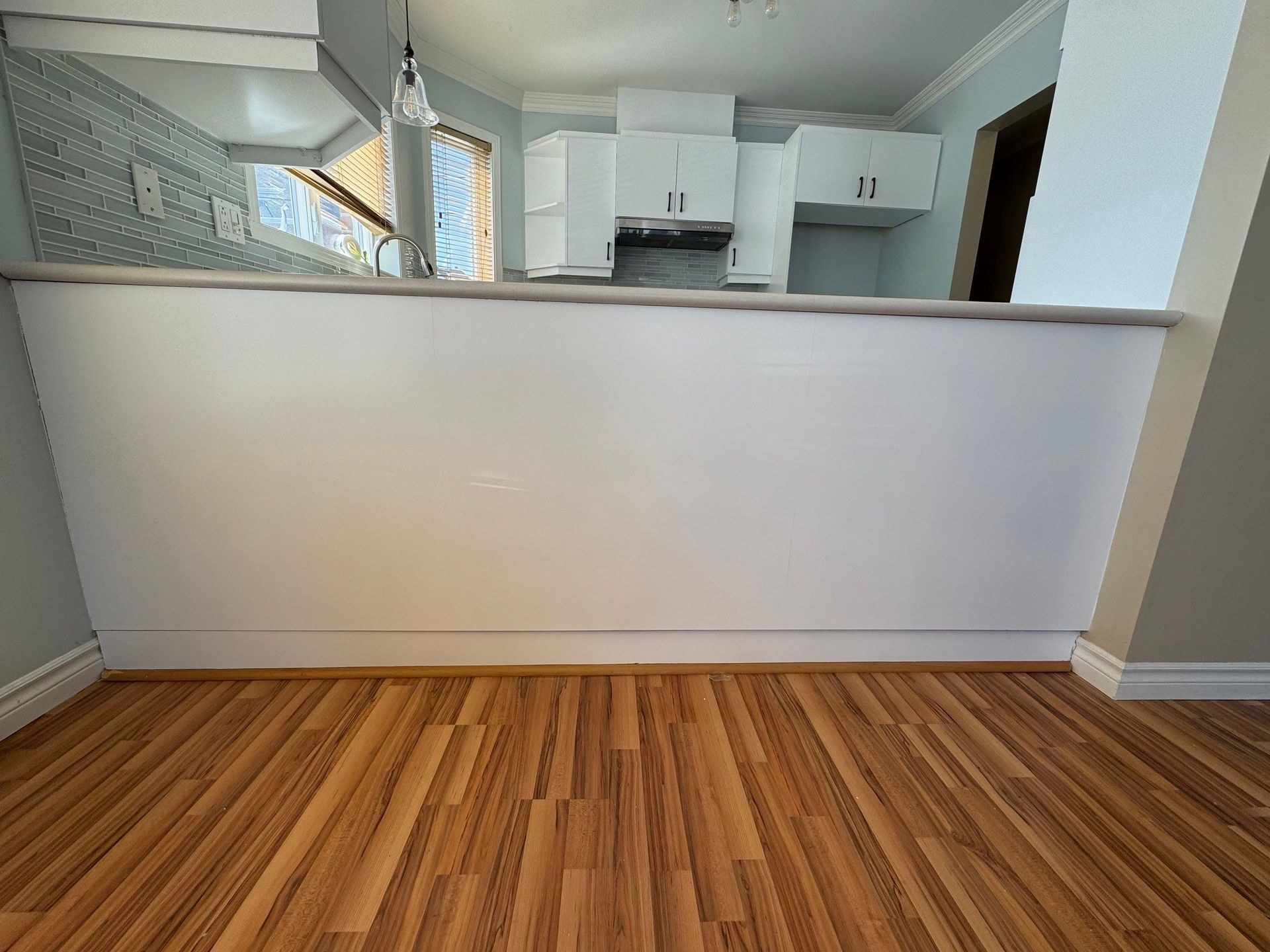 Une cuisine avec un plancher en bois et des armoires blanches