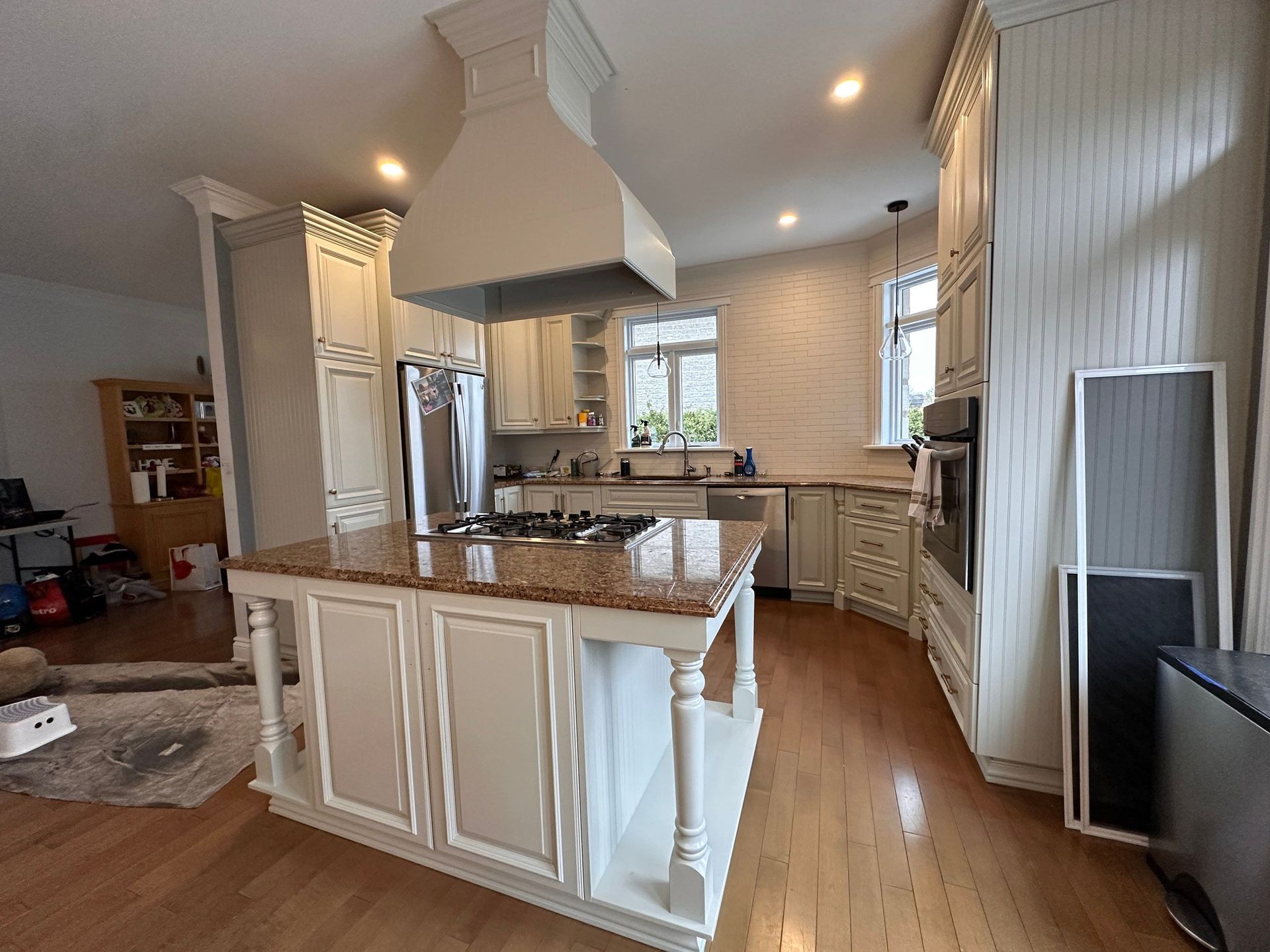 Cuisine élégante avec armoires couleur crème, îlot en granit, électroménagers en acier inoxydable et planchers de bois franc.