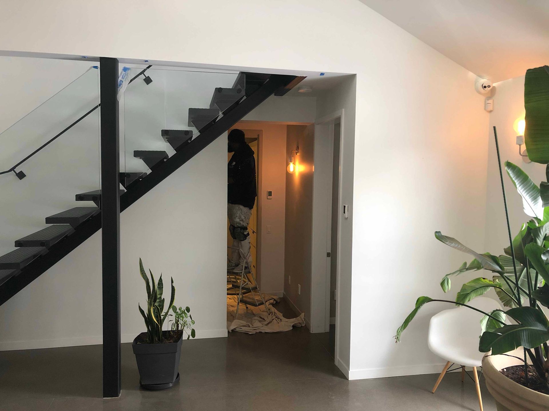 Un homme se tient sous un escalier dans un salon.
