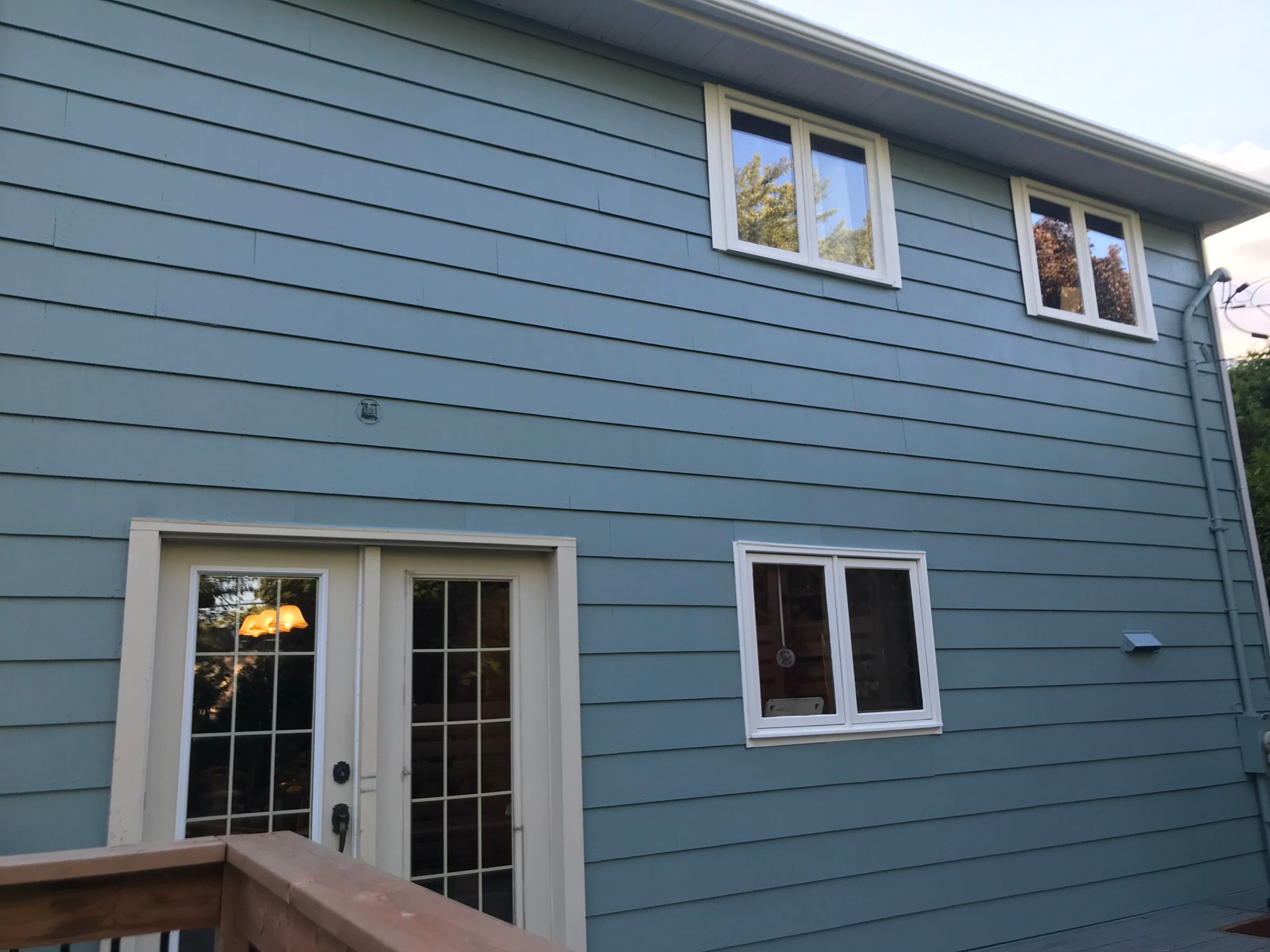 Une maison bleue avec des fenêtres blanches et une porte coulissante en verre