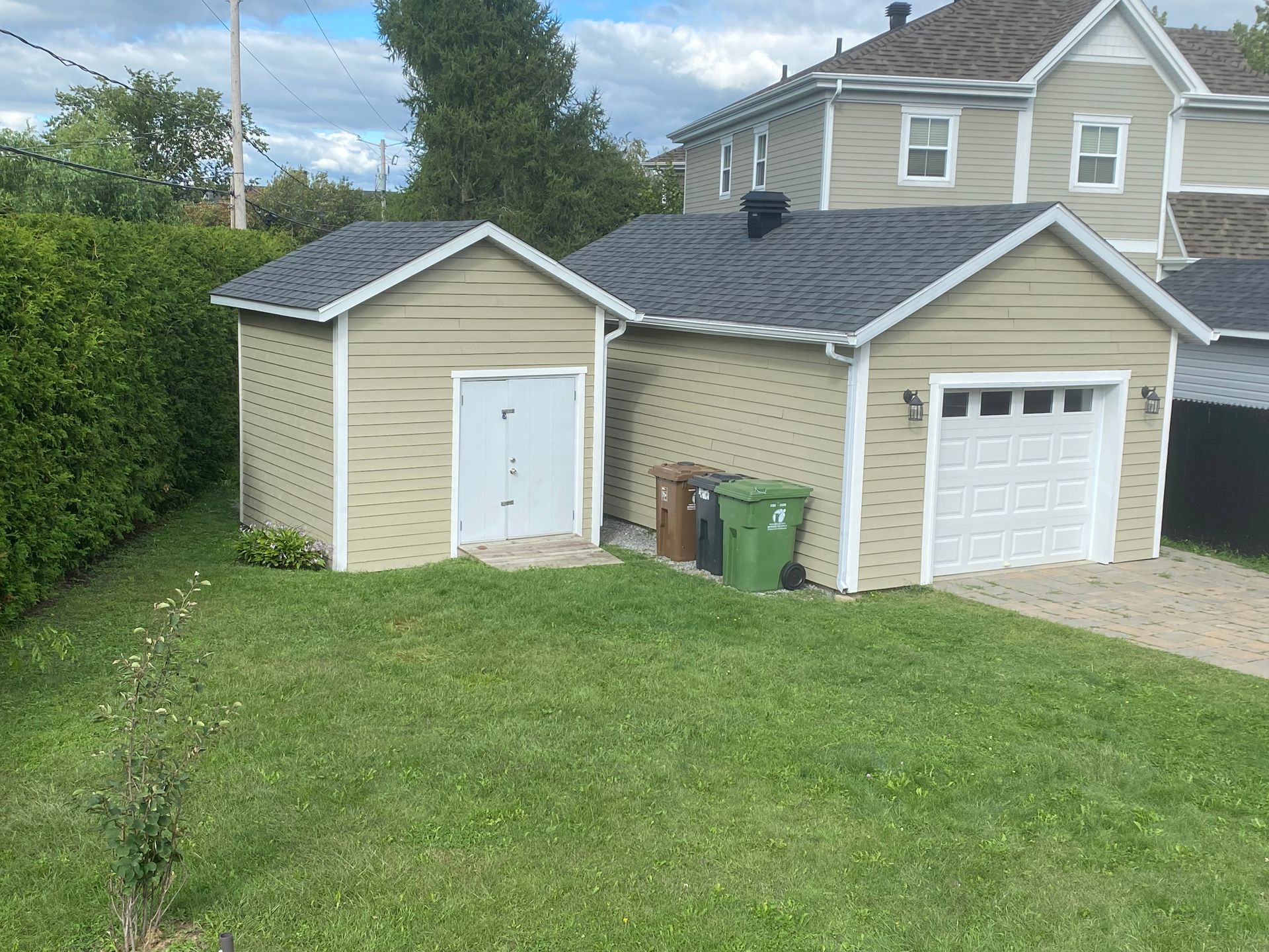 Une maison avec un garage et un hangar devant.