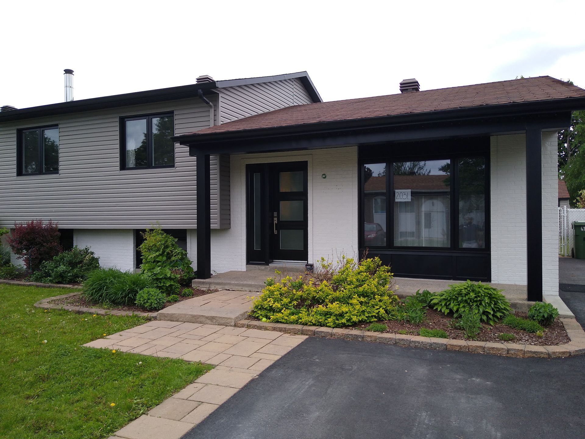 A white house with a brown roof and black trim is for sale.