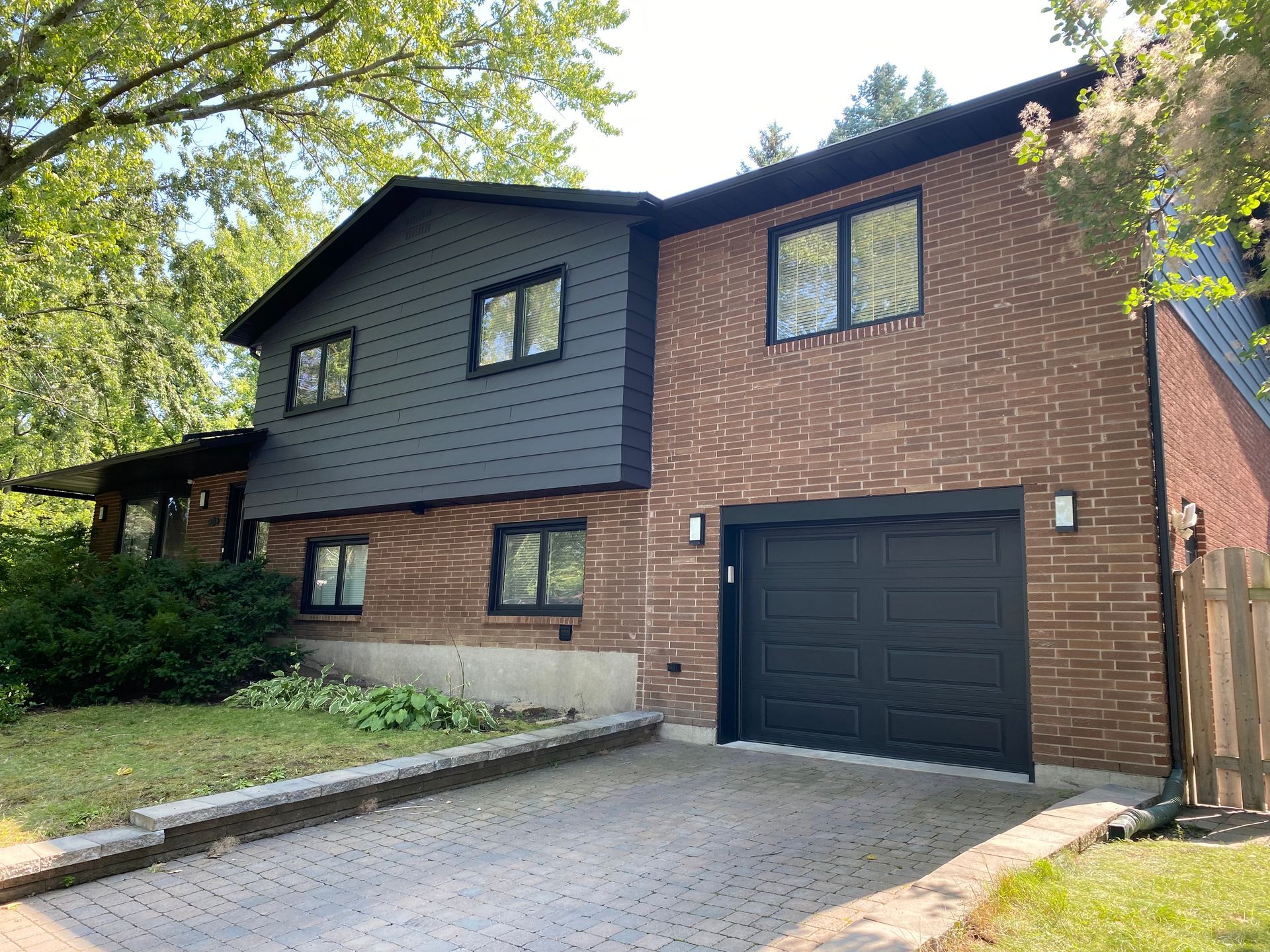 A large brick house with a black garage door and black siding.