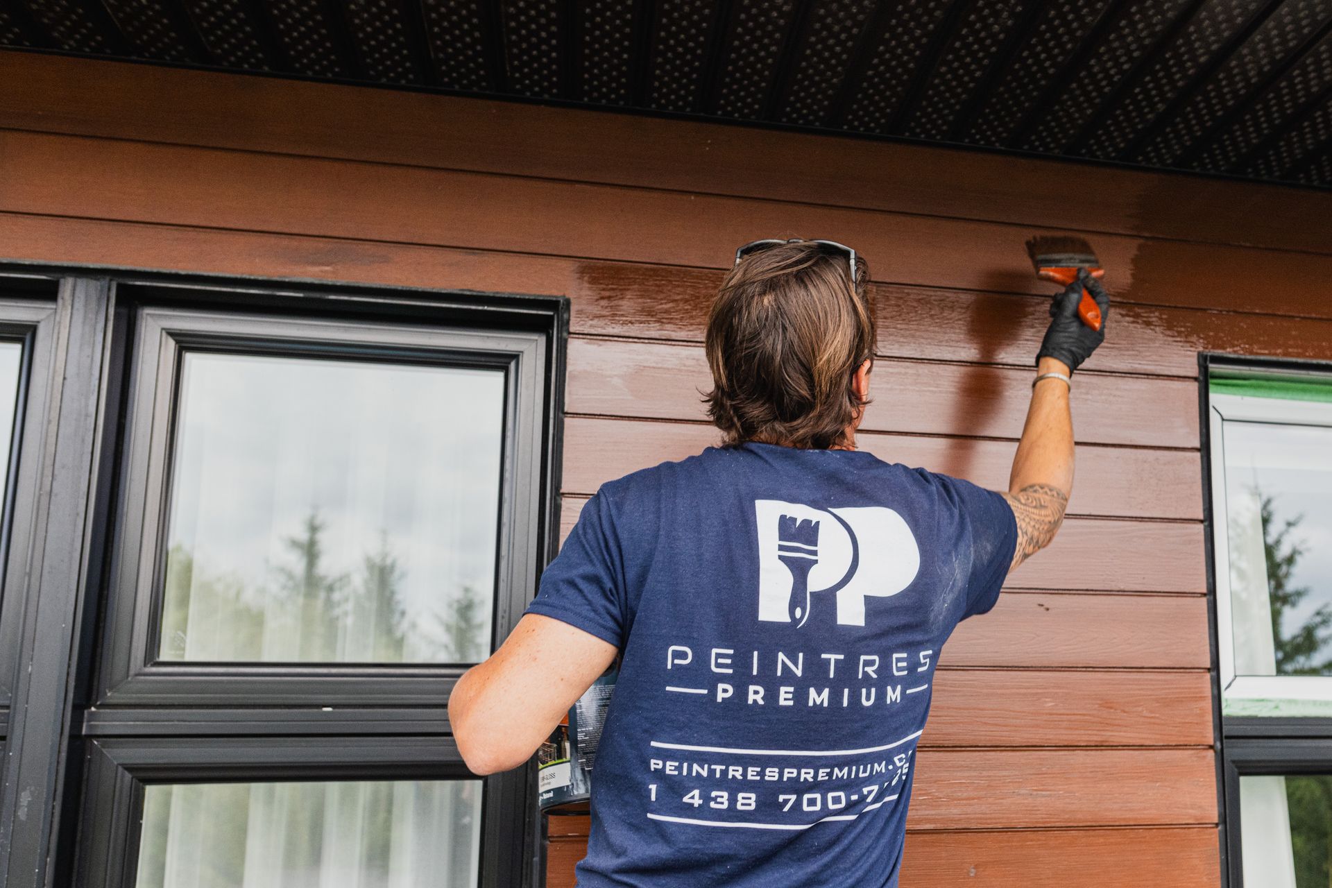 Un homme peint le côté d'une maison avec un pinceau.