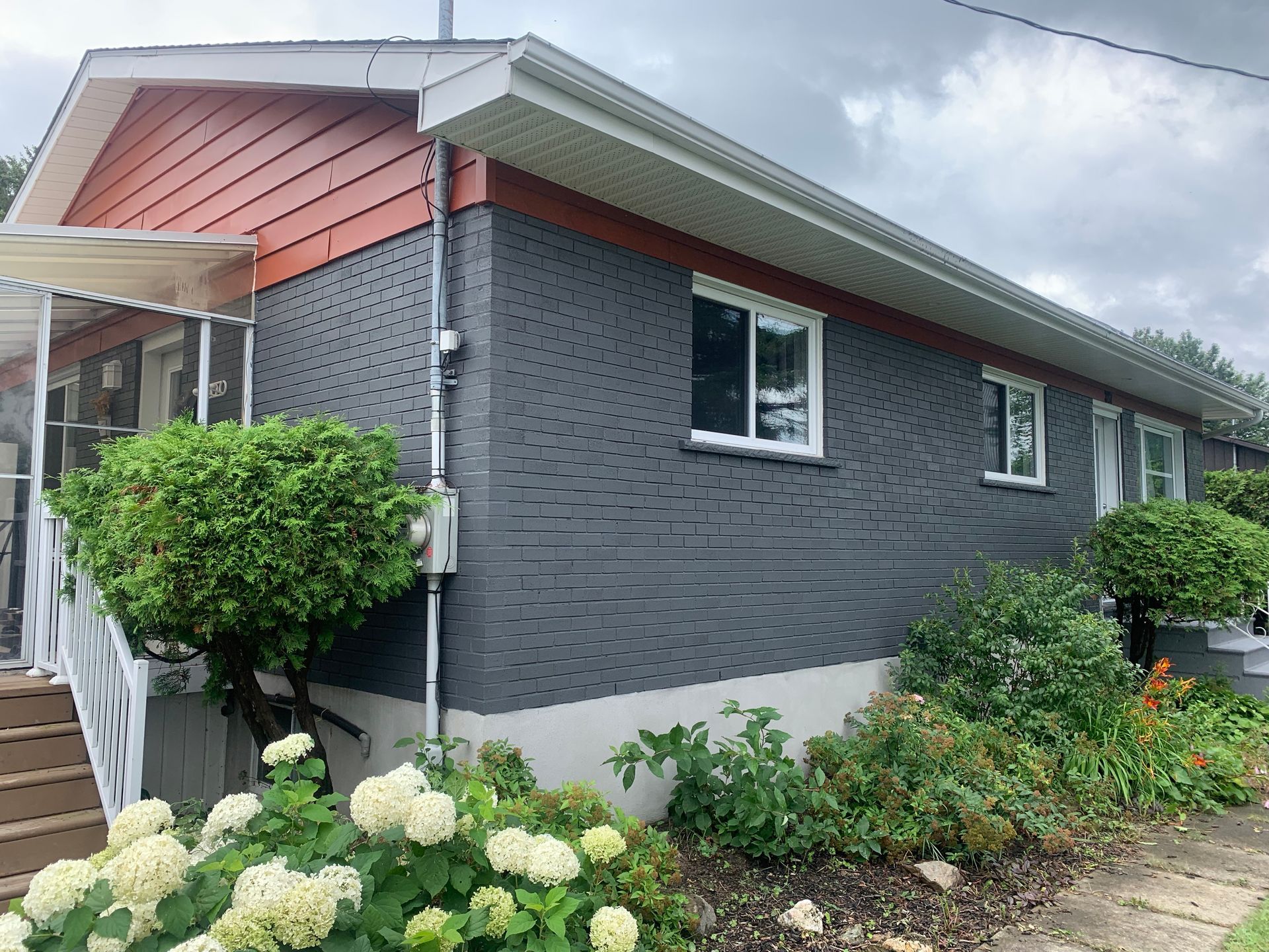 Une petite maison avec beaucoup de fenêtres et de fleurs devant.