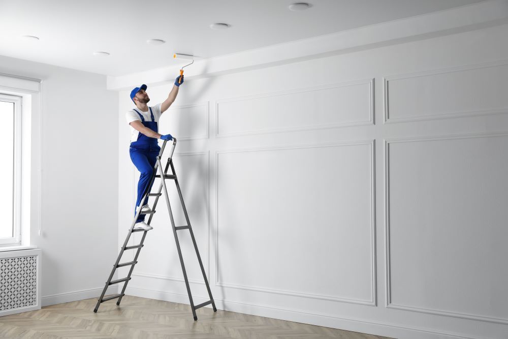 Un homme est debout sur une échelle et peint un mur.