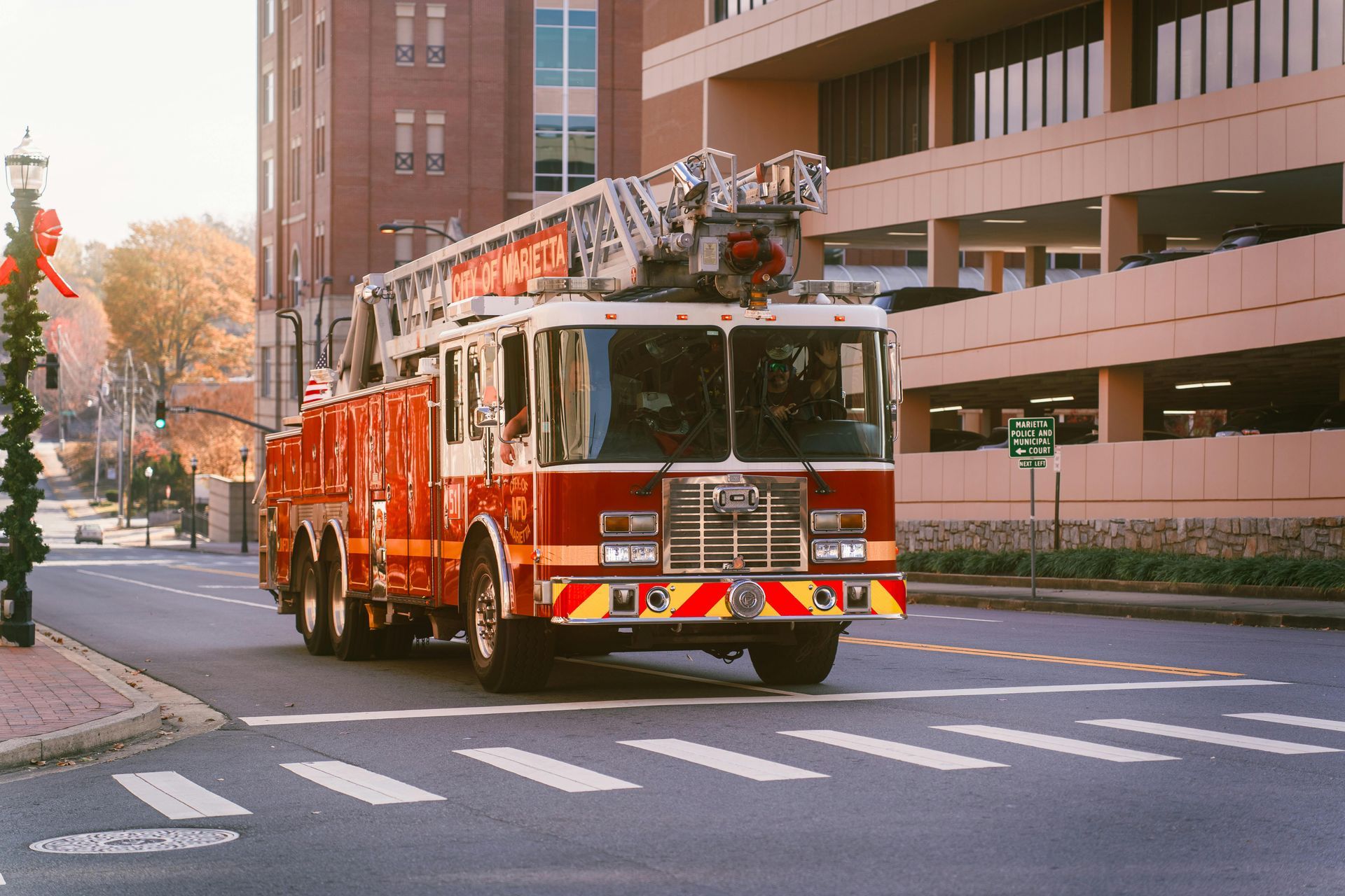 Red fire truck driving down a city street near buildings