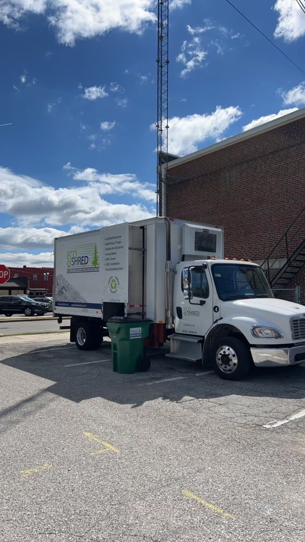 A white truck is parked in a parking lot in front of a building.