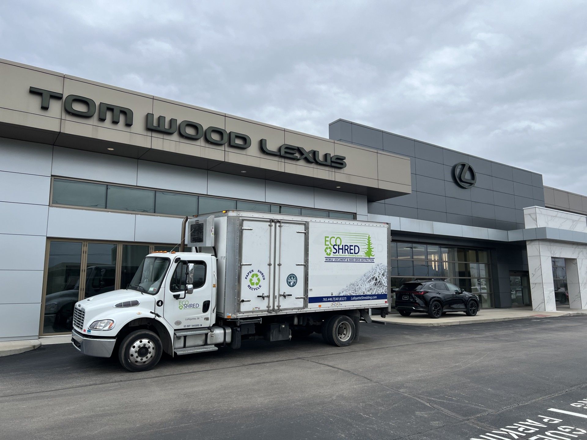 A white truck is parked in front of a tom wood lexus dealership.
