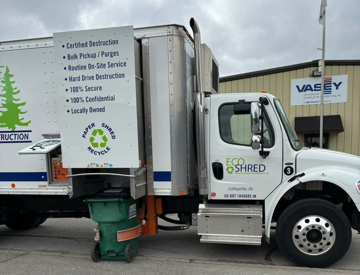 A white eco shred truck is parked in front of a building