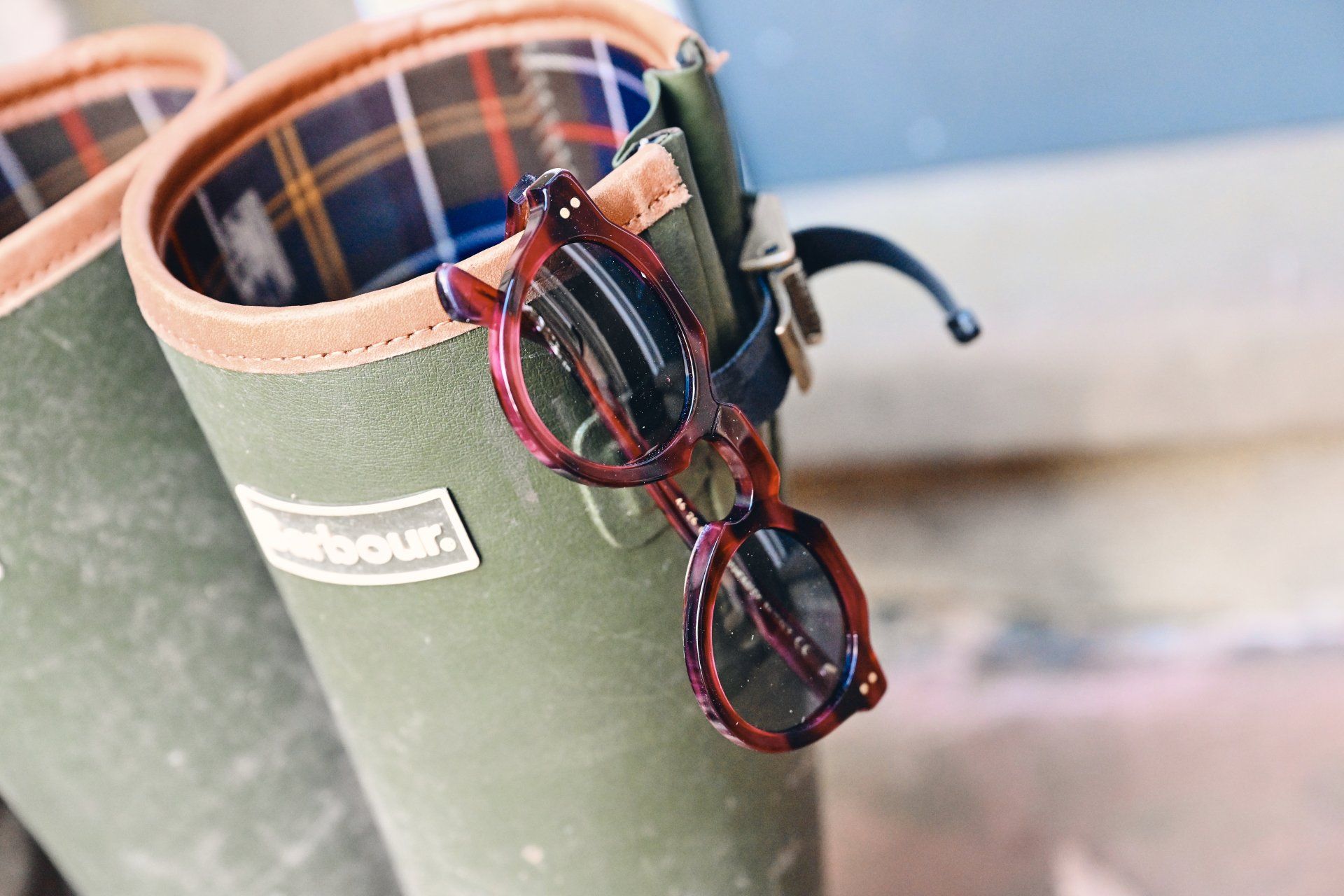Green rain boots with brown rims, hanging eyeglasses.