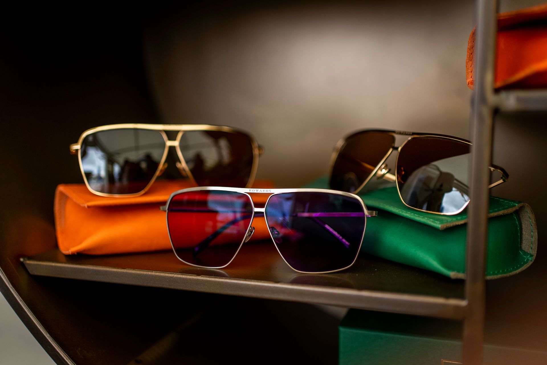 Sunglasses displayed on colorful cases within a store.