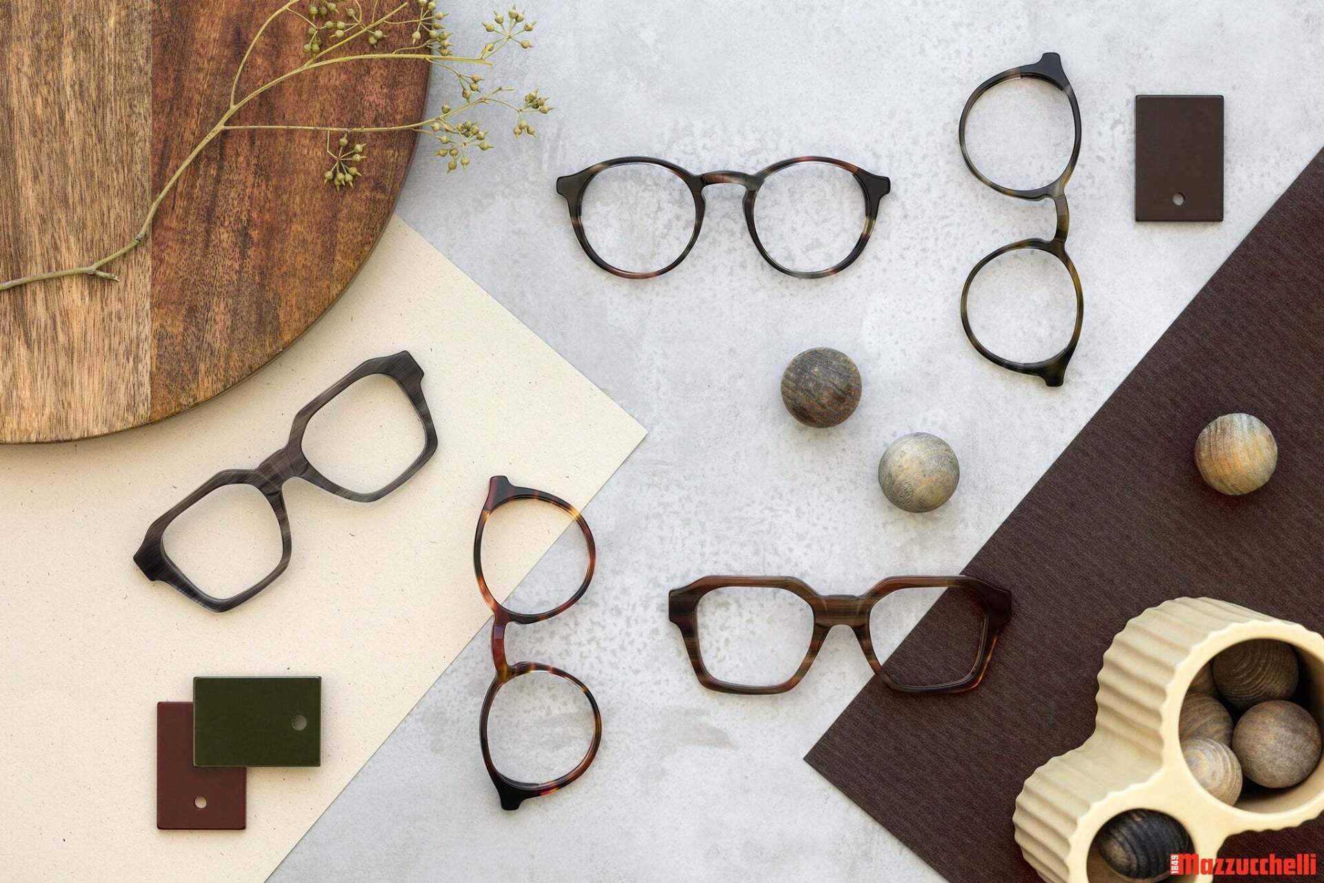 Eyeglasses arranged on a textured surface, showcasing different frame styles and colors.