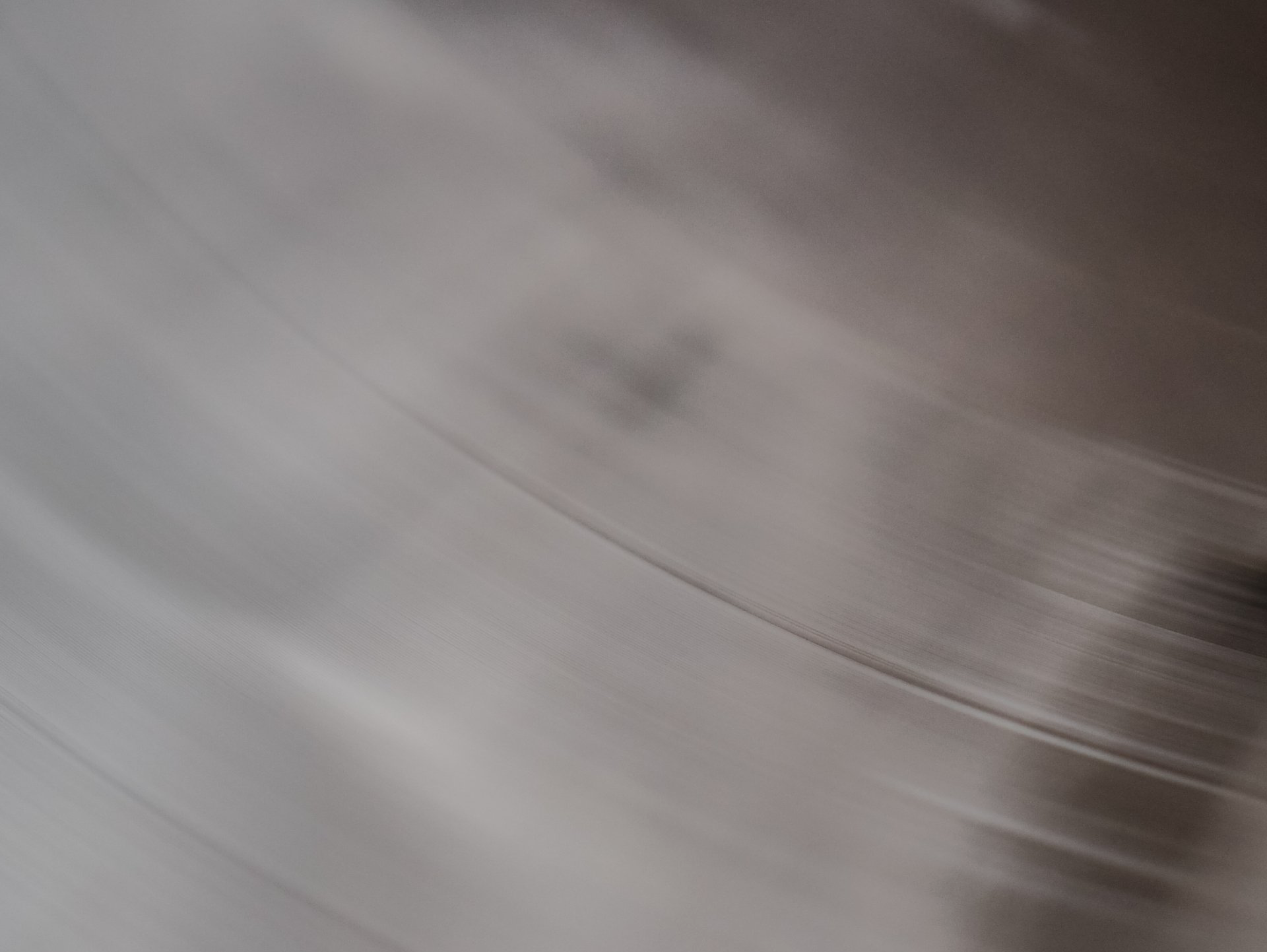 Close-up of a silver-toned, brushed metal surface with curved lines and subtle shading.