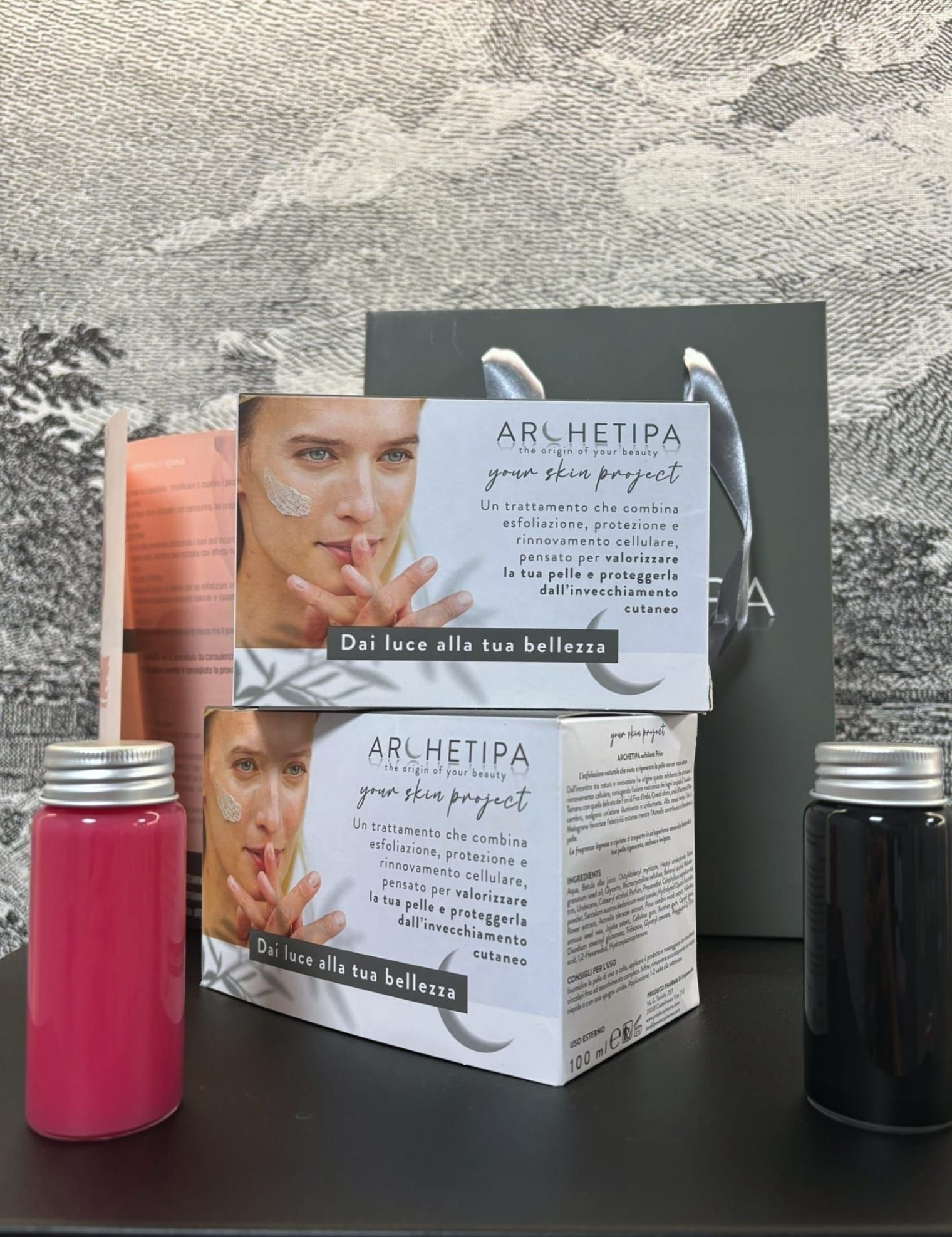 Prodotti per la cura della pelle su una superficie nera. Due scatole bianche con il volto di una donna.