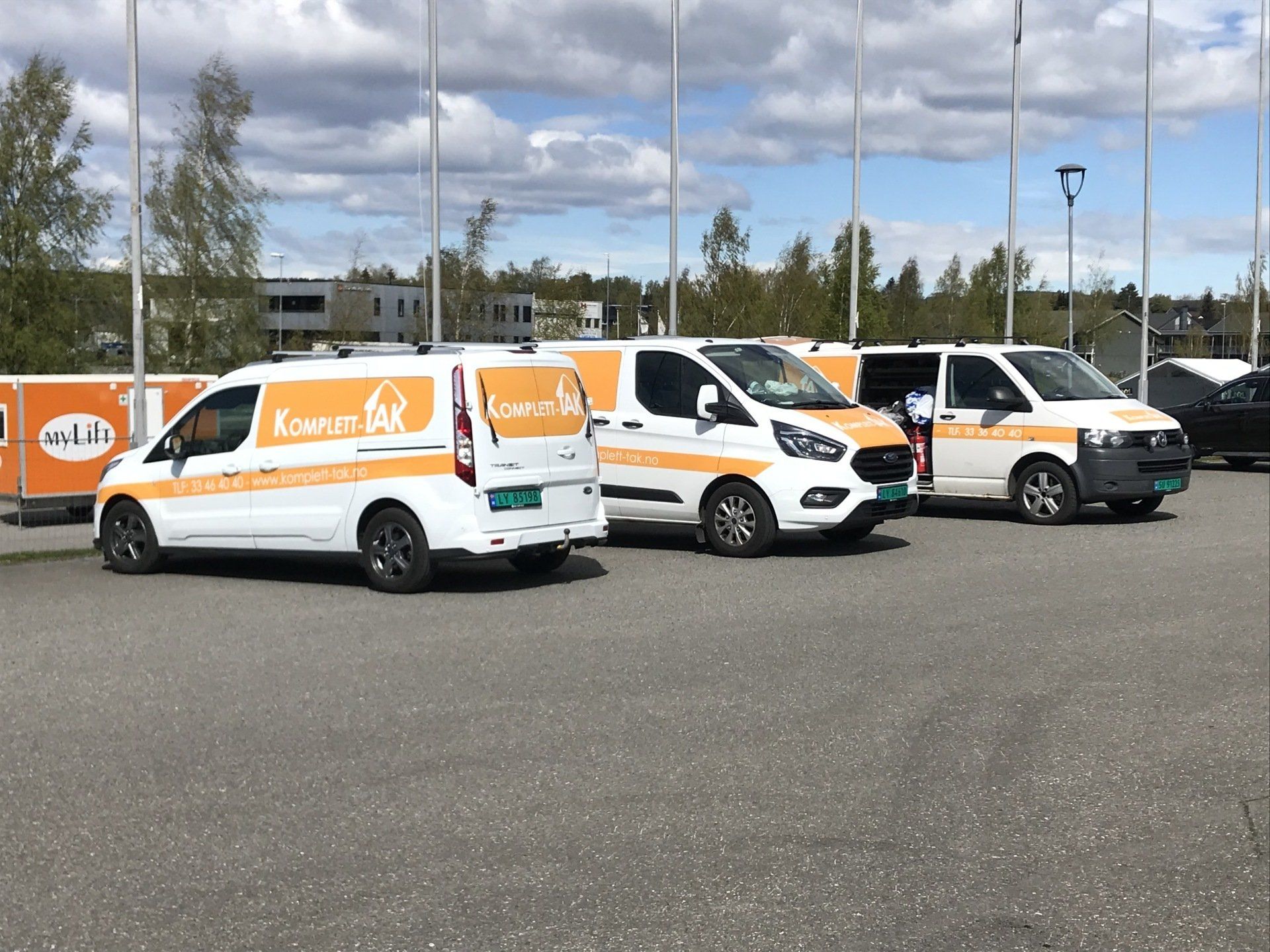 Three white vans are parked next to each other in a parking lot.