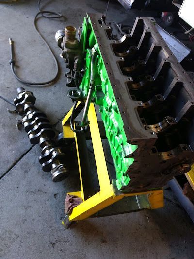 A green engine block is sitting on a yellow stand