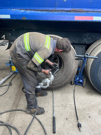 A man is working on a tire on a truck.