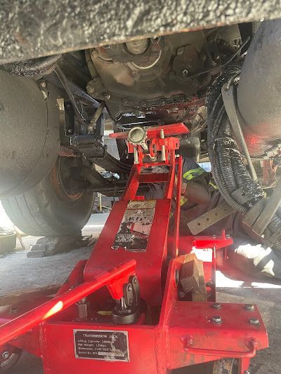 A red jack is sitting underneath a car.