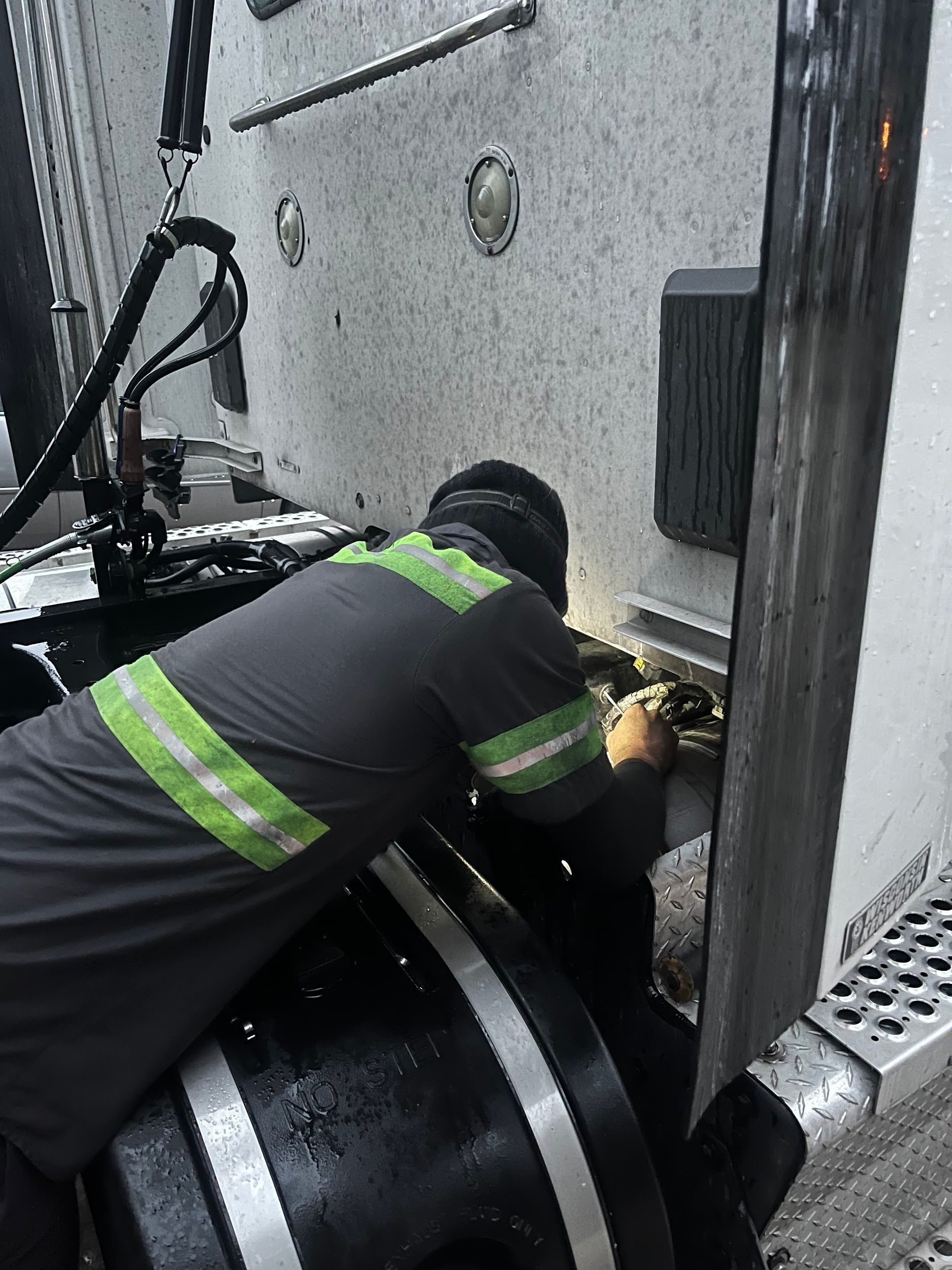 A man is working on the back of a semi truck.