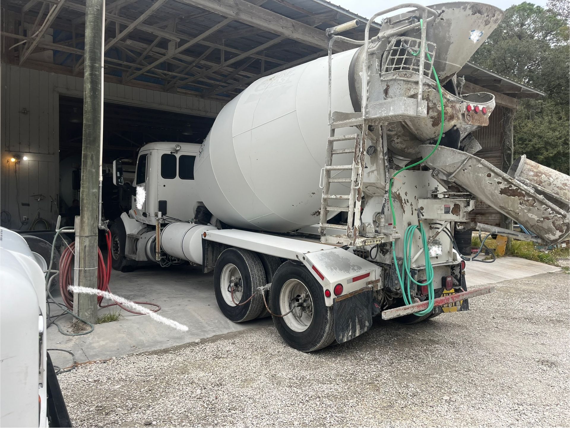 A concrete mixer truck is parked in front of a building.