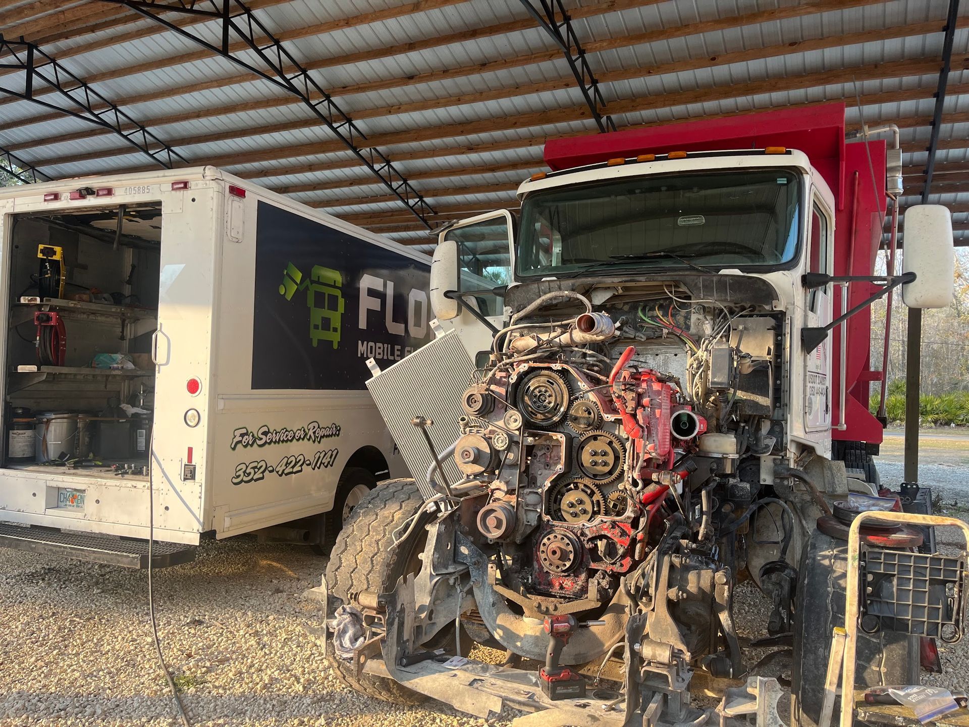 A truck is being repaired in a garage under a roof.