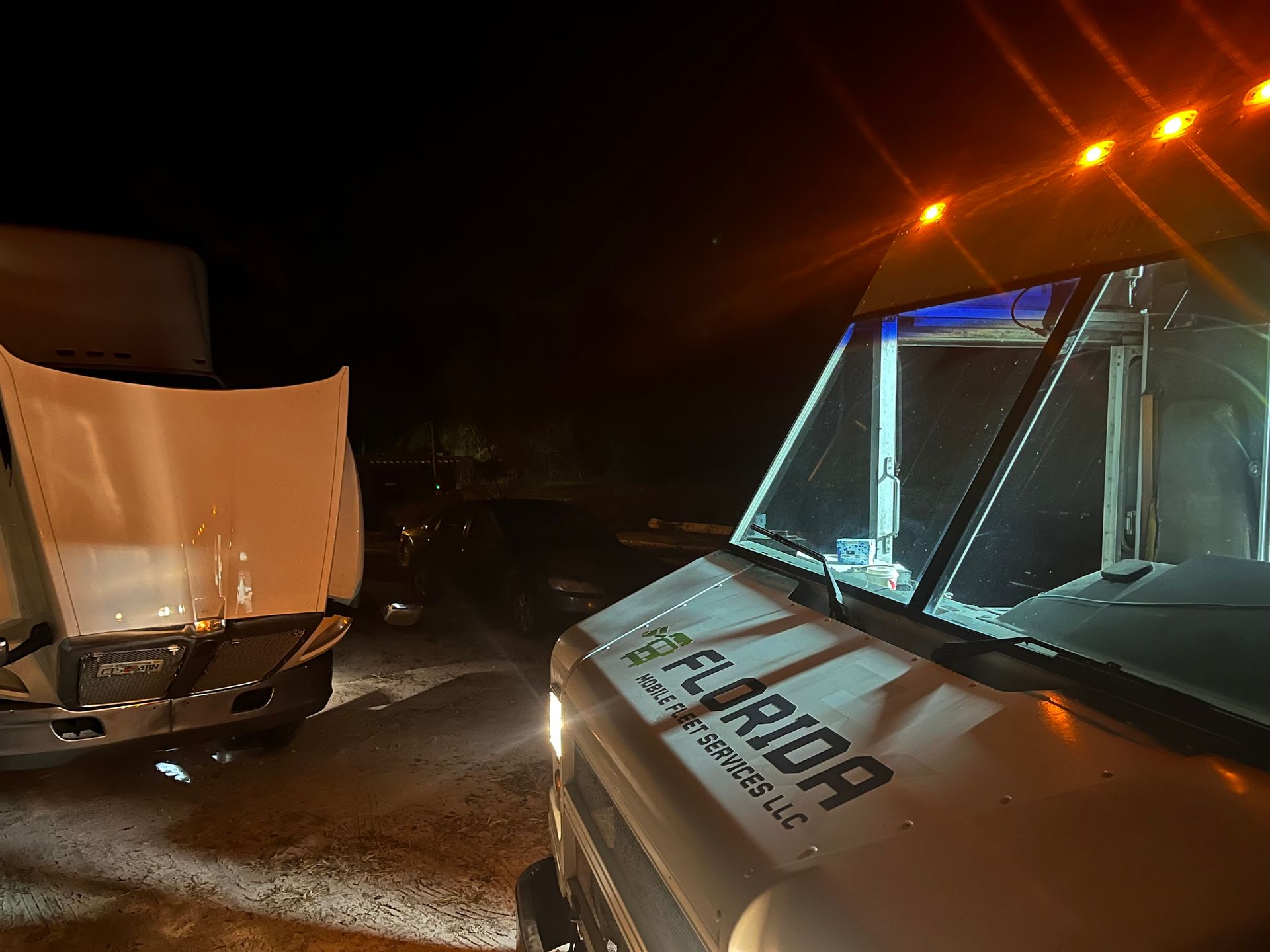 A florida truck is parked in the dark with its hood open.