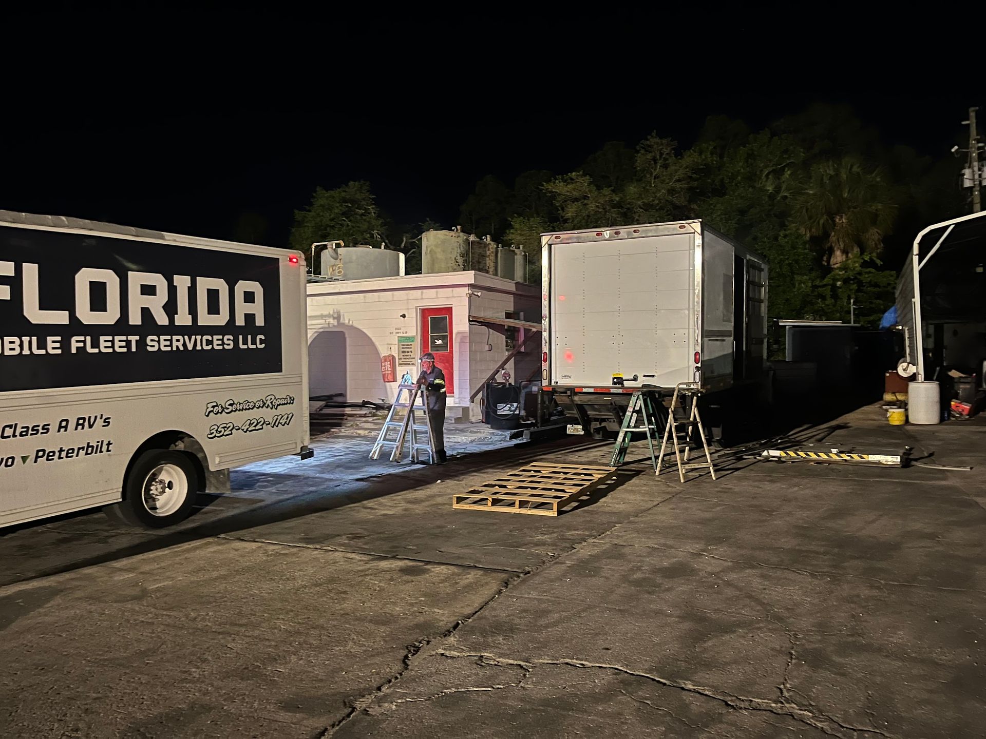 A florida mobile fleet services truck is parked in a parking lot at night.